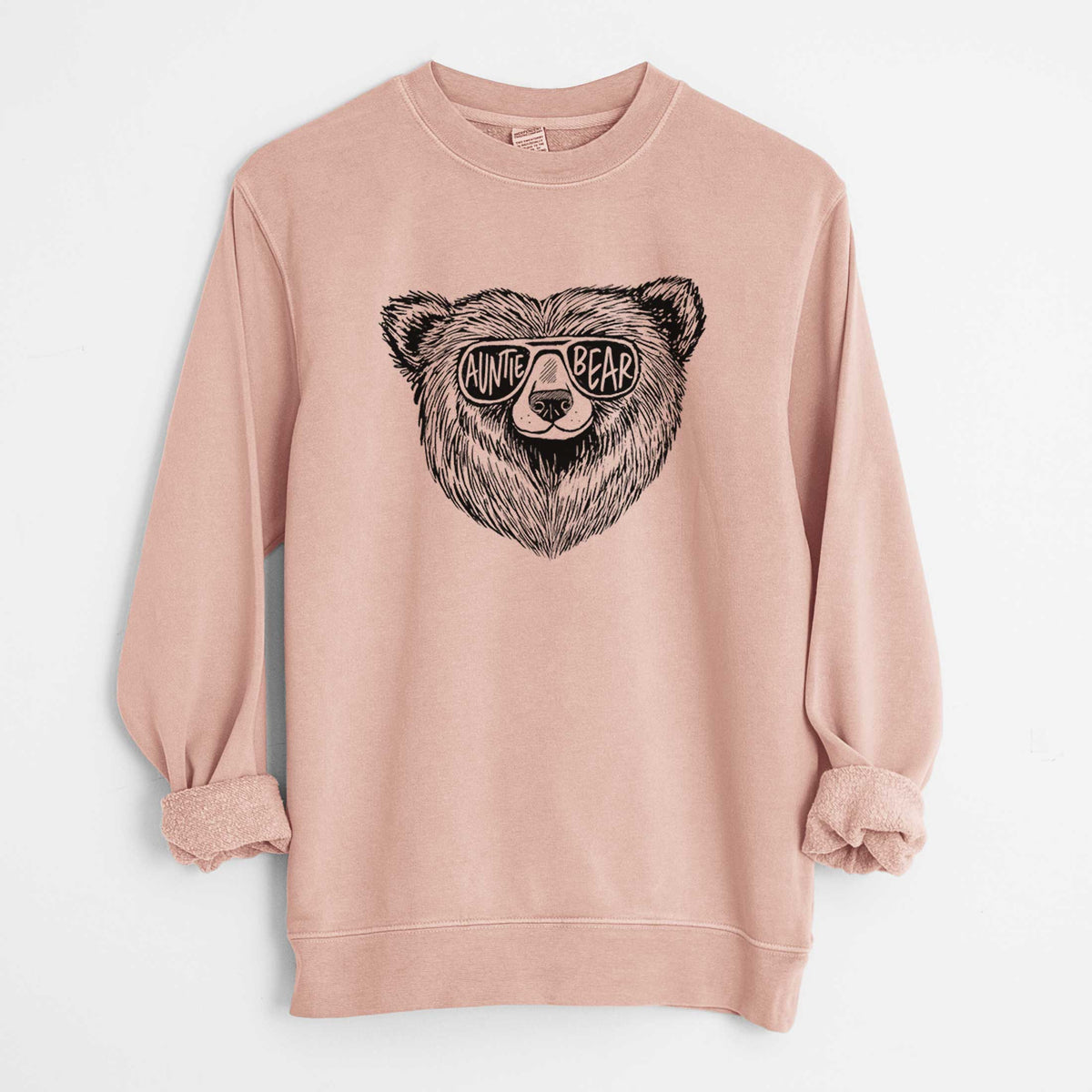 Dusty pink pigment dyed crewneck sweatshirt laid flat with the sleeves rolled, printed with a black ink bear's face wearing sunglasses that read Auntie Bear.