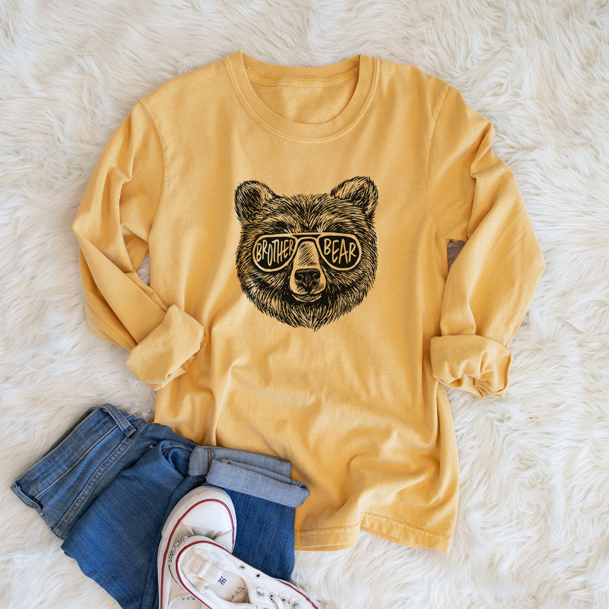 Golden wheat yellow Comfort Colors long sleeve shirt printed with a black ink bear's face wearing sunglasses that read Brother Bear, shown in a lifestyle photo.