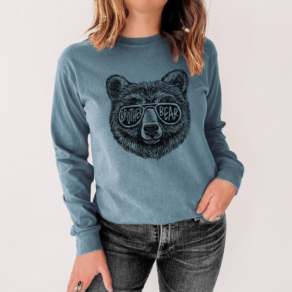 Steel blue Comfort Colors long sleeve shirt printed with a black ink bear's face wearing sunglasses that read Brother Bear, shown in a lifestyle photo.