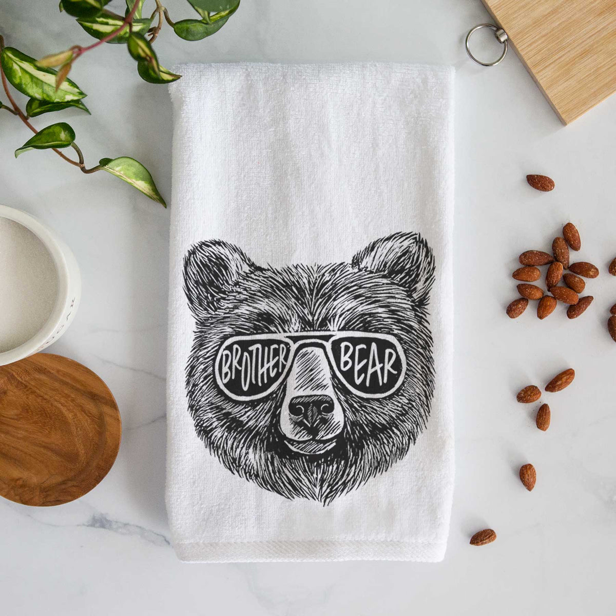 White hand towel printed with a black ink bear's face wearing sunglasses that read Brother Bear.