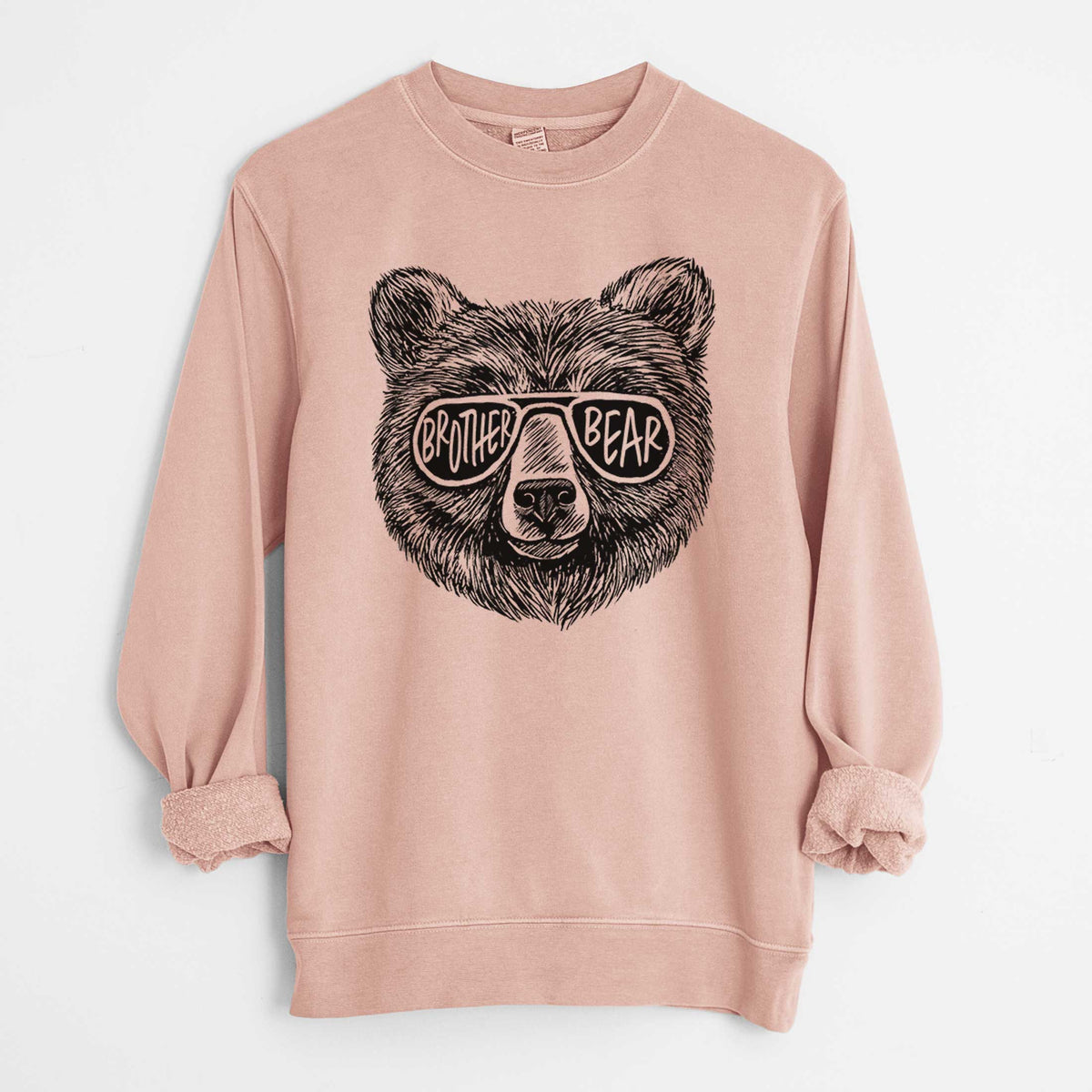 Dusty pink pigment dyed crewneck sweatshirt laid flat with the sleeves rolled, printed with a black ink bear's face wearing sunglasses that read Brother Bear.