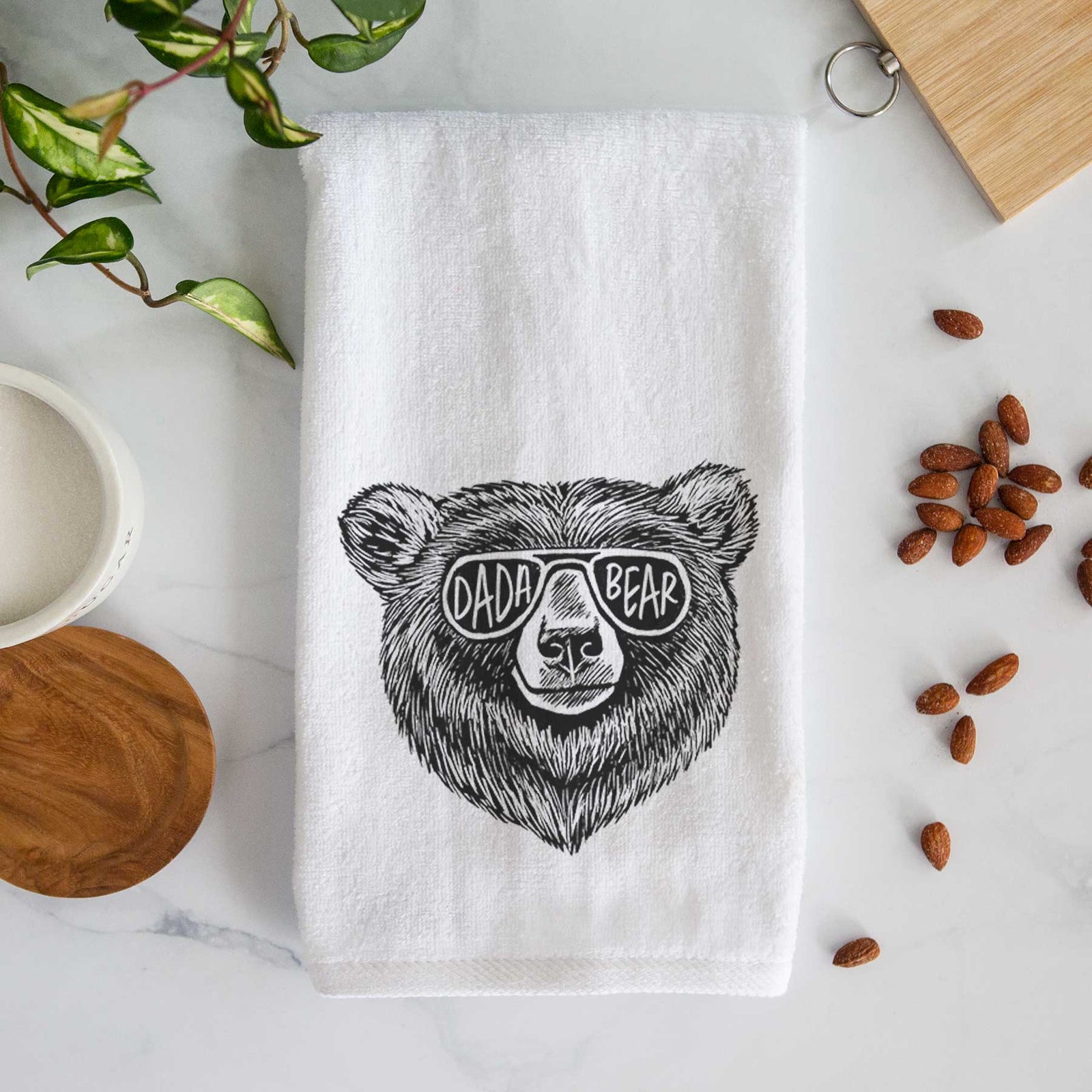 White hand towel printed with a black ink bear's face wearing sunglasses that read Dada Bear.