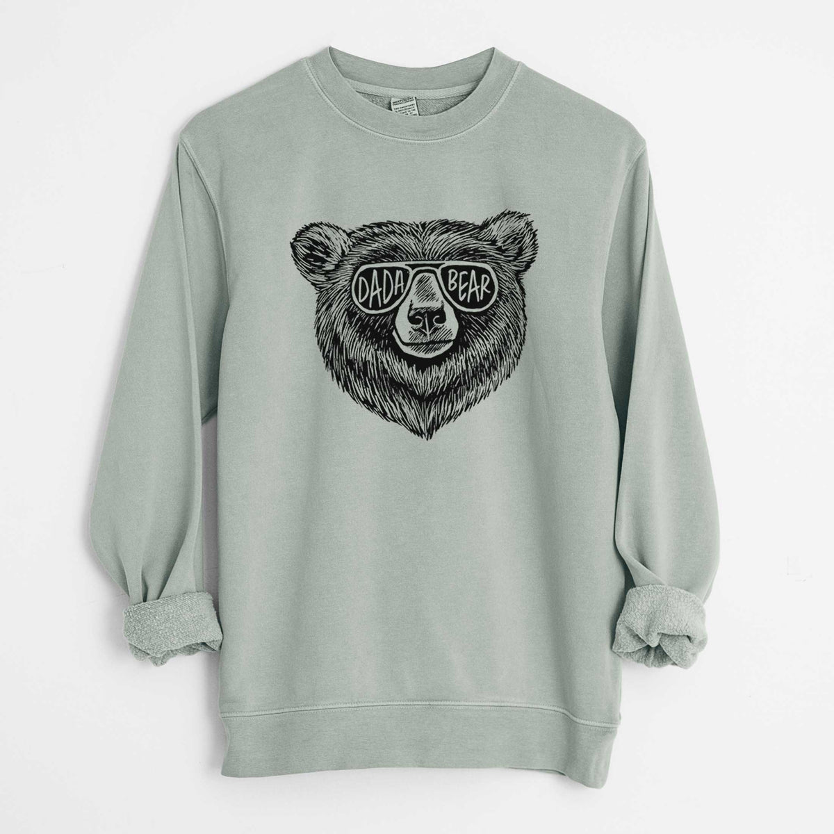 Sage green pigment dyed crewneck sweatshirt laid flat with the sleeves rolled, printed with a black ink bear's face wearing sunglasses that read Dada Bear.