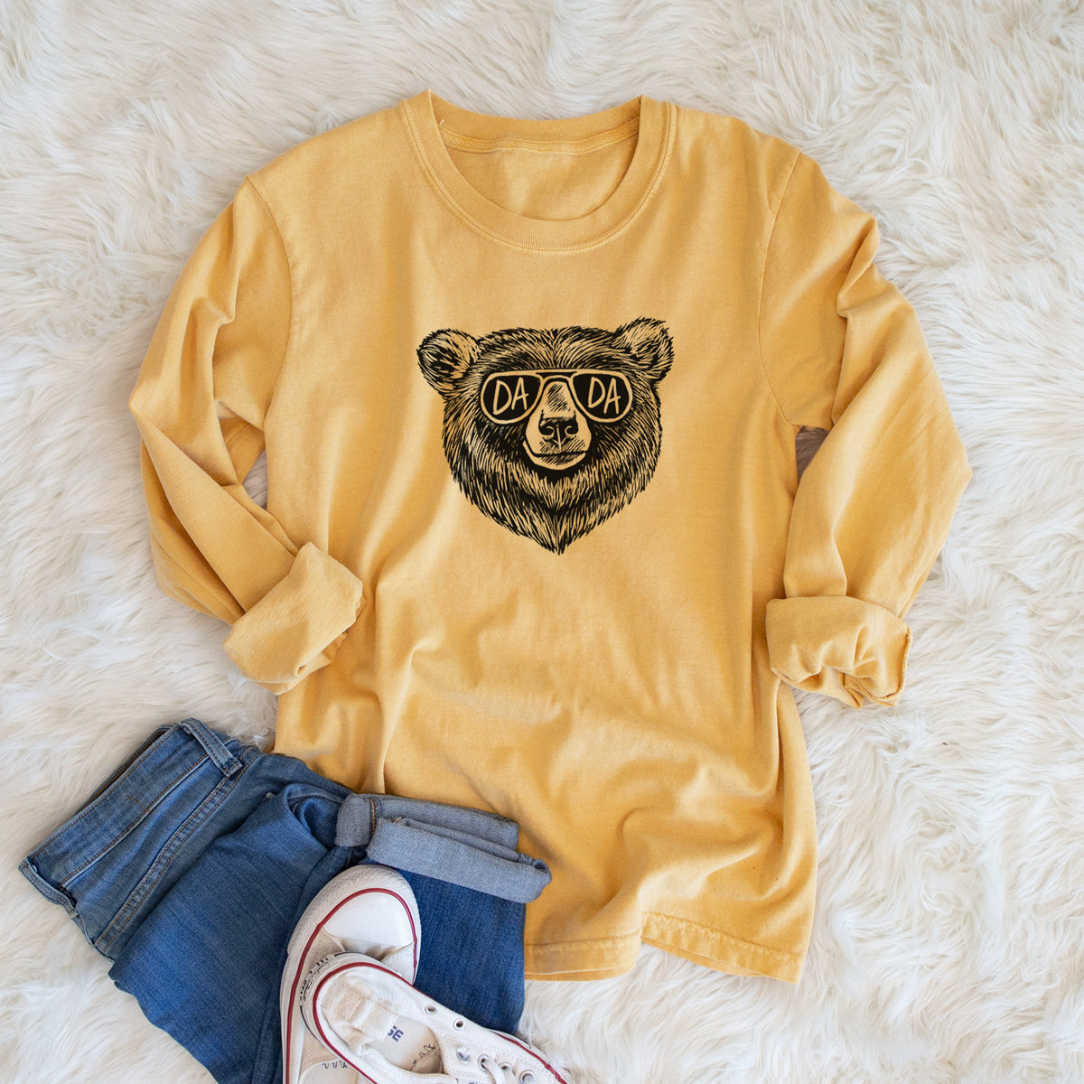 Golden wheat yellow Comfort Colors long sleeve shirt printed with a black ink bear's face wearing sunglasses that read Dada, shown in a lifestyle photo.