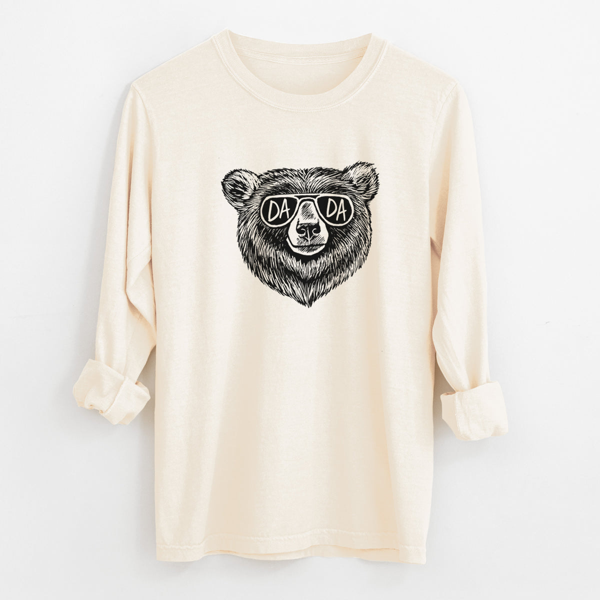 Ivory Comfort Colors long sleeve shirt laid flat with the cuffs rolled, printed with a black ink bear's face wearing sunglasses that read Dada.