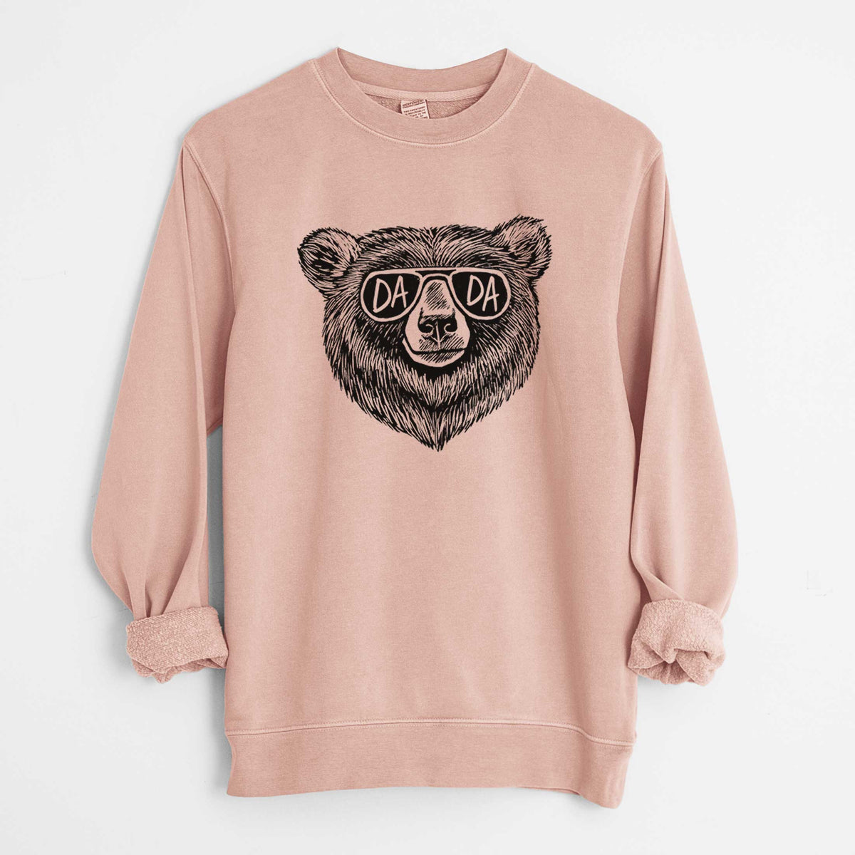 Dusty pink pigment dyed crewneck sweatshirt laid flat with the sleeves rolled, printed with a black ink bear's face wearing sunglasses that read Dada.