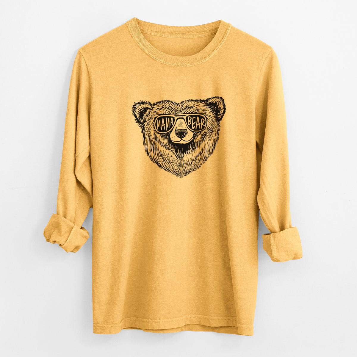 Golden wheat yellow Comfort Colors long sleeve shirt laid flat with the cuffs rolled, printed with a black ink bear's face wearing sunglasses that read Mama Bear.