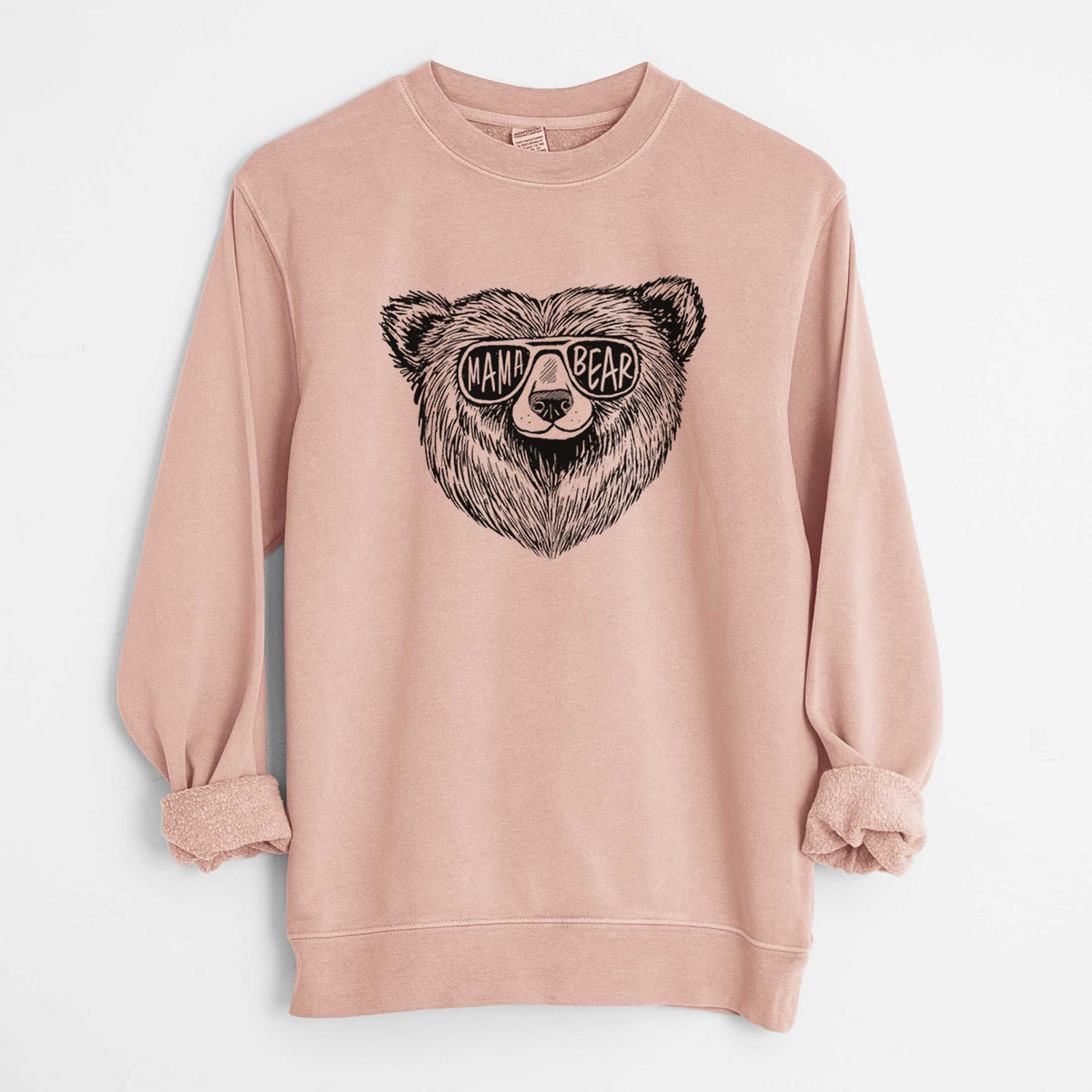 Dusty pink pigment dyed crewneck sweatshirt laid flat with the sleeves rolled, printed with a black ink bear's face wearing sunglasses that read Mama Bear.