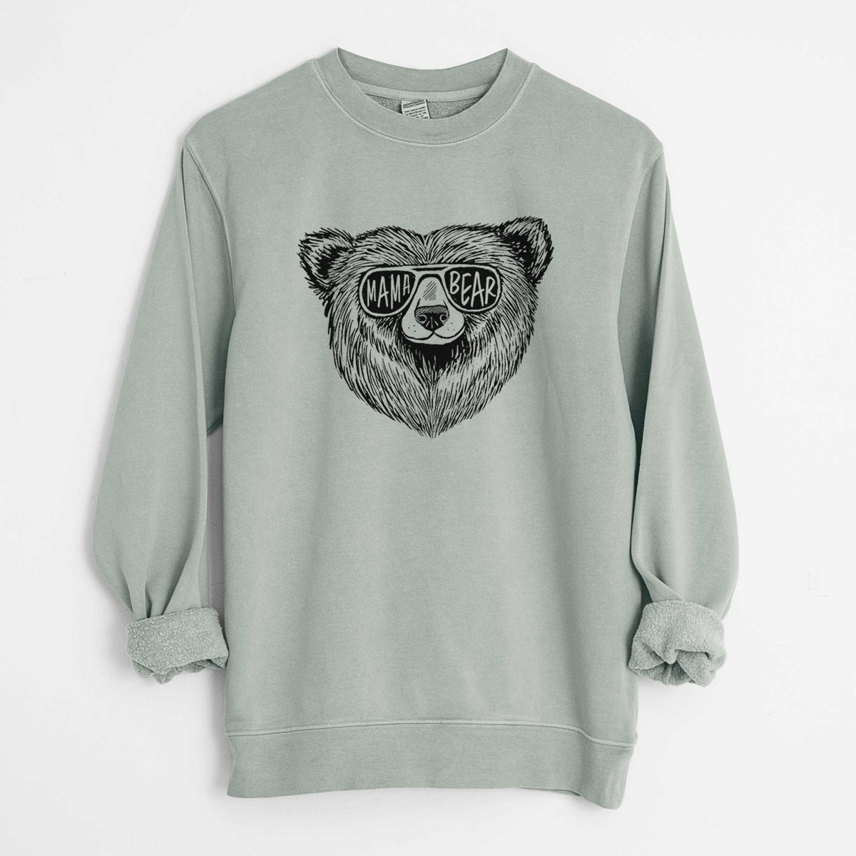 Sage green pigment dyed crewneck sweatshirt laid flat with the sleeves rolled, printed with a black ink bear's face wearing sunglasses that read Mama Bear.