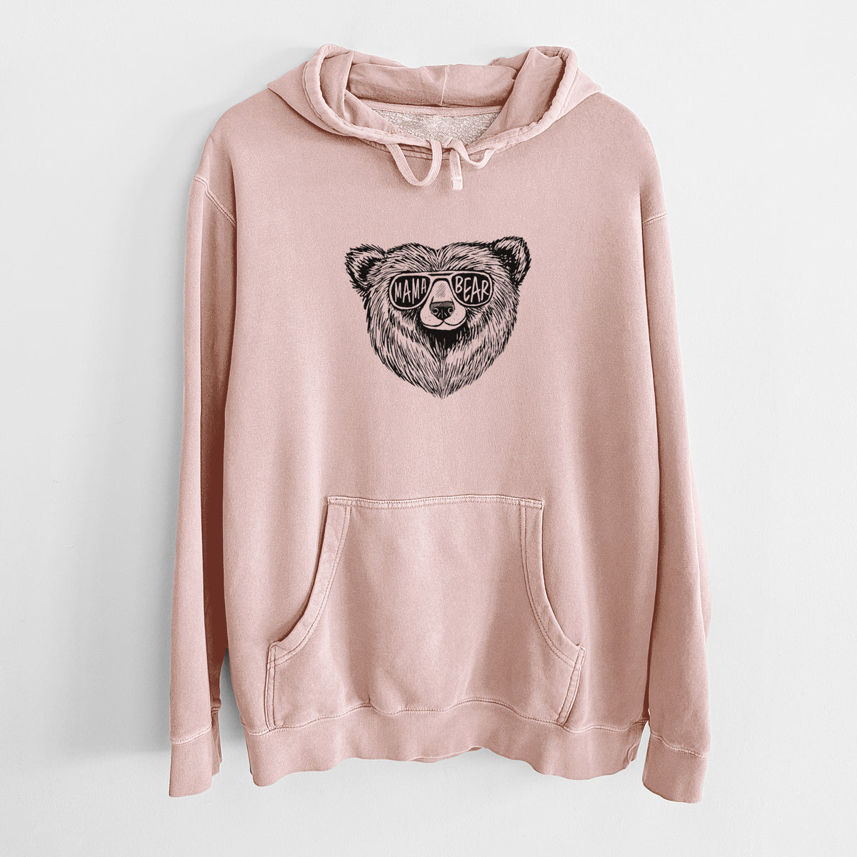Dusty pink pigment dyed hoodie laid flat, printed with a black ink bear's face wearing sunglasses that read Mama Bear.