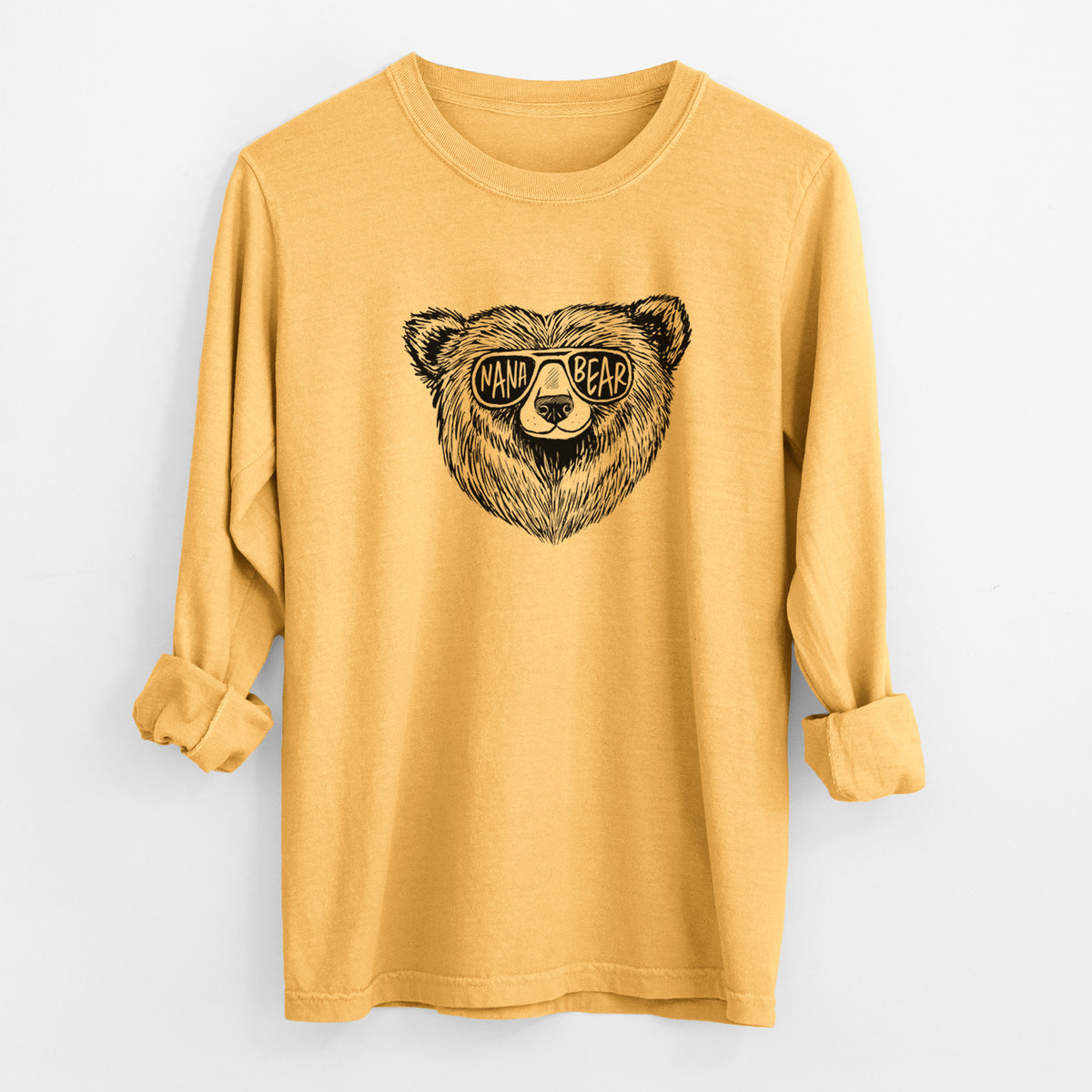 Golden wheat yellow Comfort Colors long sleeve shirt laid flat with the cuffs rolled, printed with a black ink bear's face wearing sunglasses that read Nana Bear.