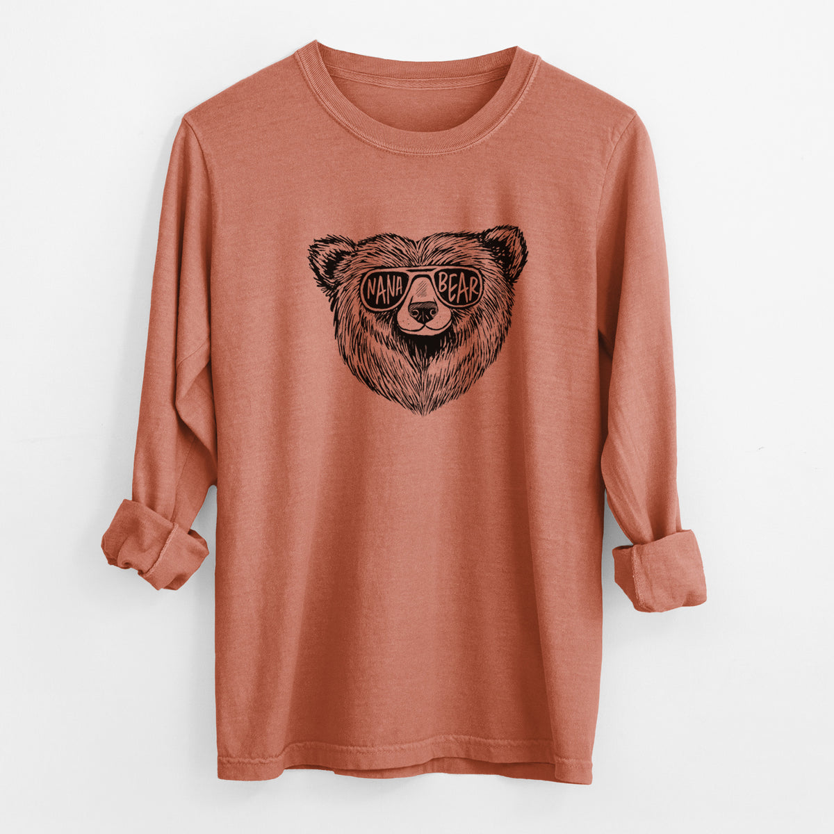 Yam burnt orange Comfort Colors long sleeve shirt laid flat with the cuffs rolled, printed with a black ink bear's face wearing sunglasses that read Nana Bear.