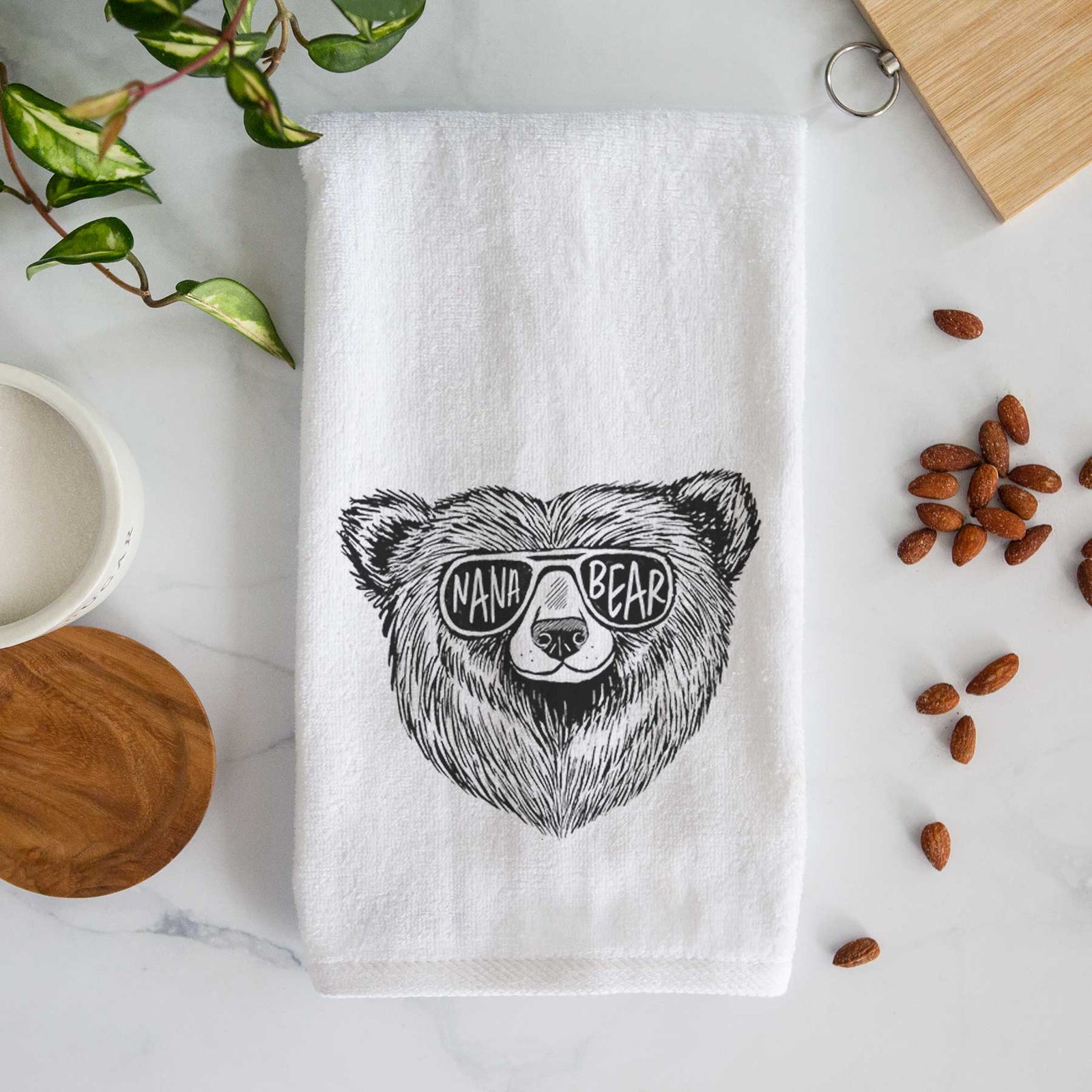 White hand towel printed with a black ink bear's face wearing sunglasses that read Nana Bear.