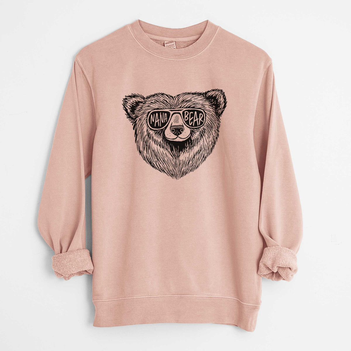 Dusty pink pigment dyed crewneck sweatshirt laid flat with the sleeves rolled, printed with a black ink bear's face wearing sunglasses that read Nana Bear.