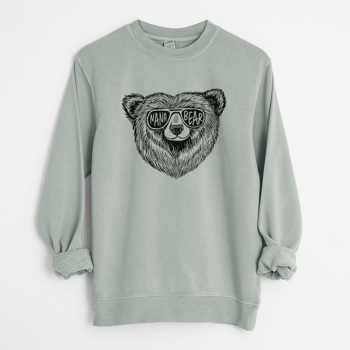 Sage green pigment dyed crewneck sweatshirt laid flat with the sleeves rolled, printed with a black ink bear's face wearing sunglasses that read Nana Bear.