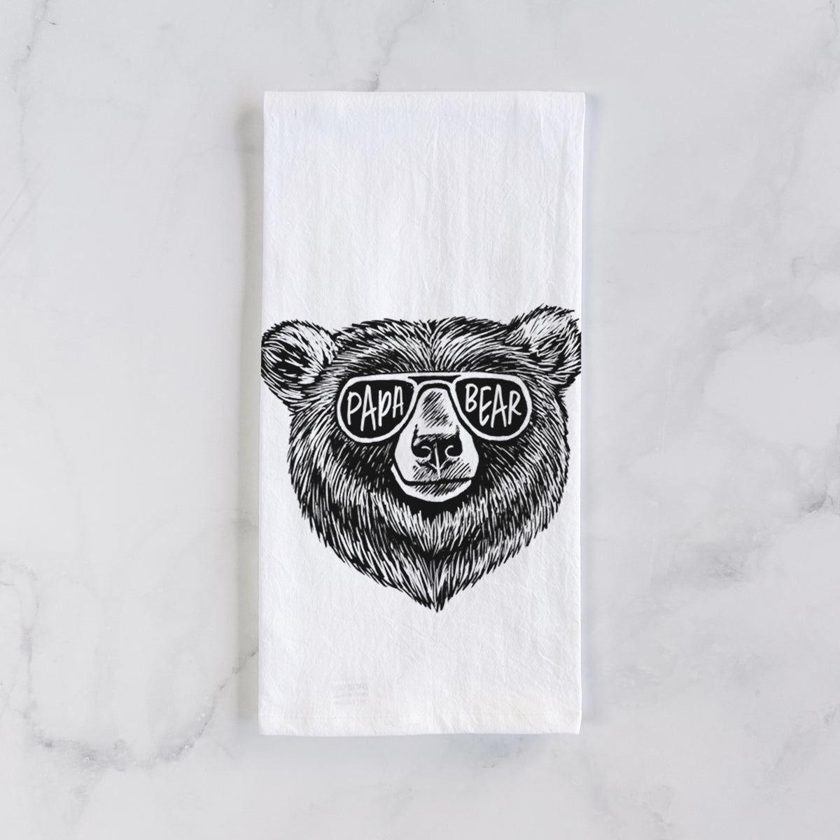 White cotton tea towel laid flat on marble, printed with a black ink bear's face wearing sunglasses that read Papa Bear.