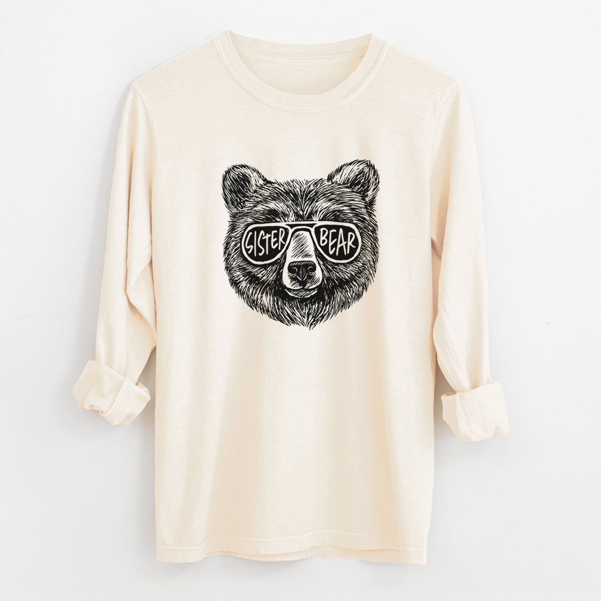 Ivory Comfort Colors long sleeve shirt laid flat with the cuffs rolled, printed with a black ink bear's face wearing sunglasses that read Sister Bear.