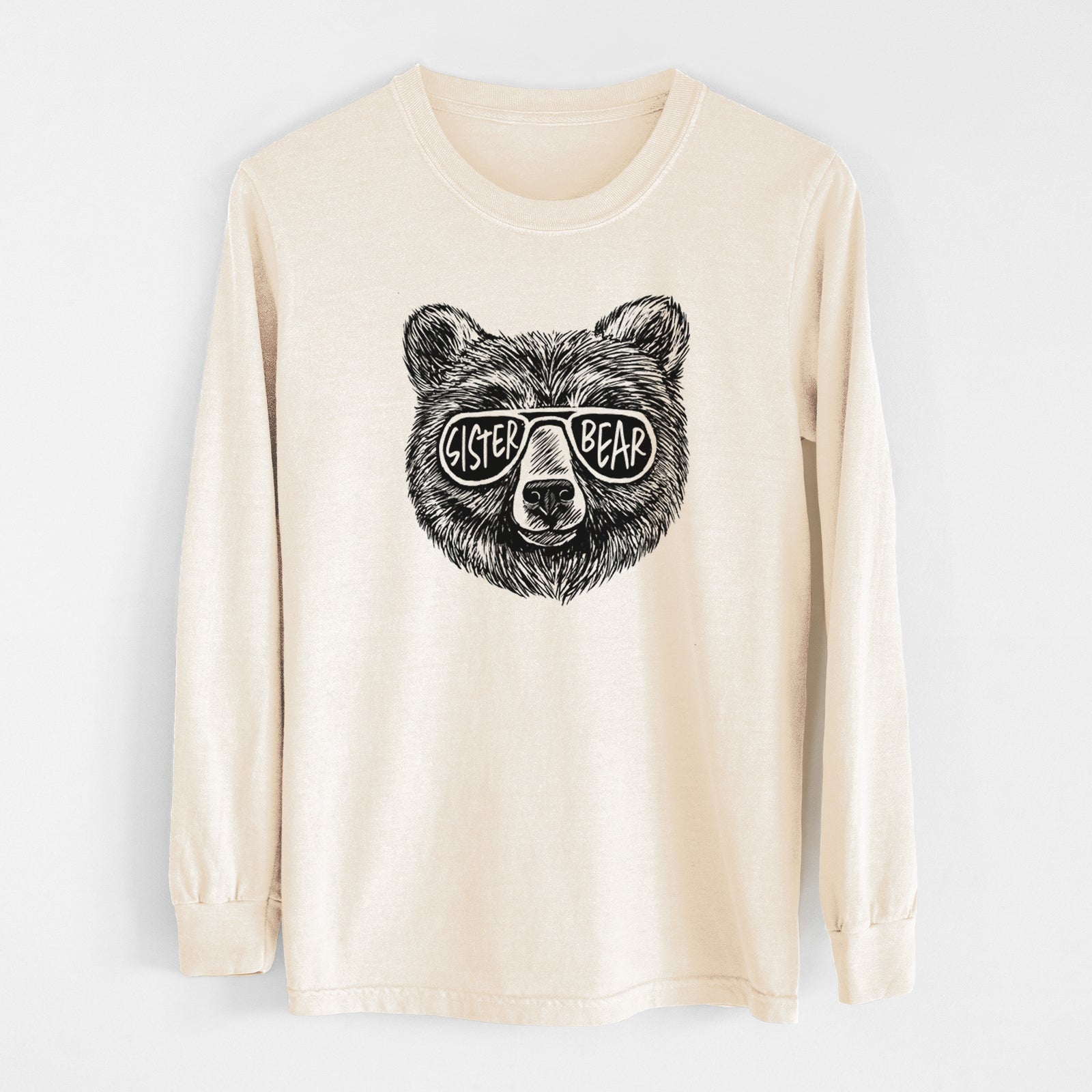 Ivory Comfort Colors long sleeve shirt laid flat, printed with a black ink bear's face wearing sunglasses that read Sister Bear.