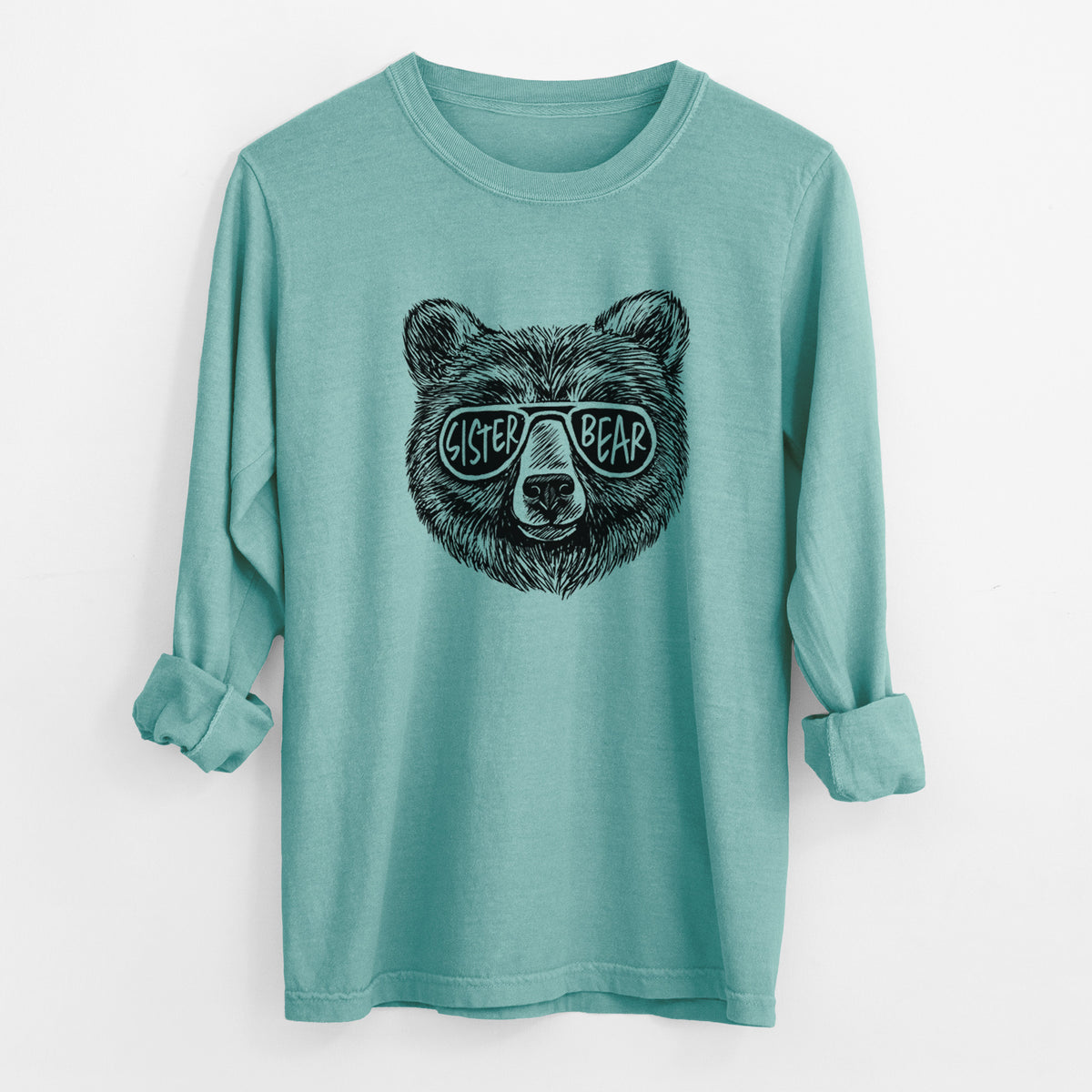 Reef green Comfort Colors long sleeve shirt laid flat with the cuffs rolled, printed with a black ink bear's face wearing sunglasses that read Sister Bear.