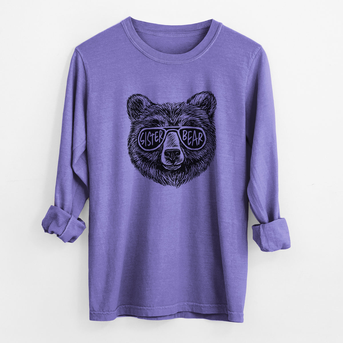 Violet purple Comfort Colors long sleeve shirt laid flat with the cuffs rolled, printed with a black ink bear's face wearing sunglasses that read Sister Bear.