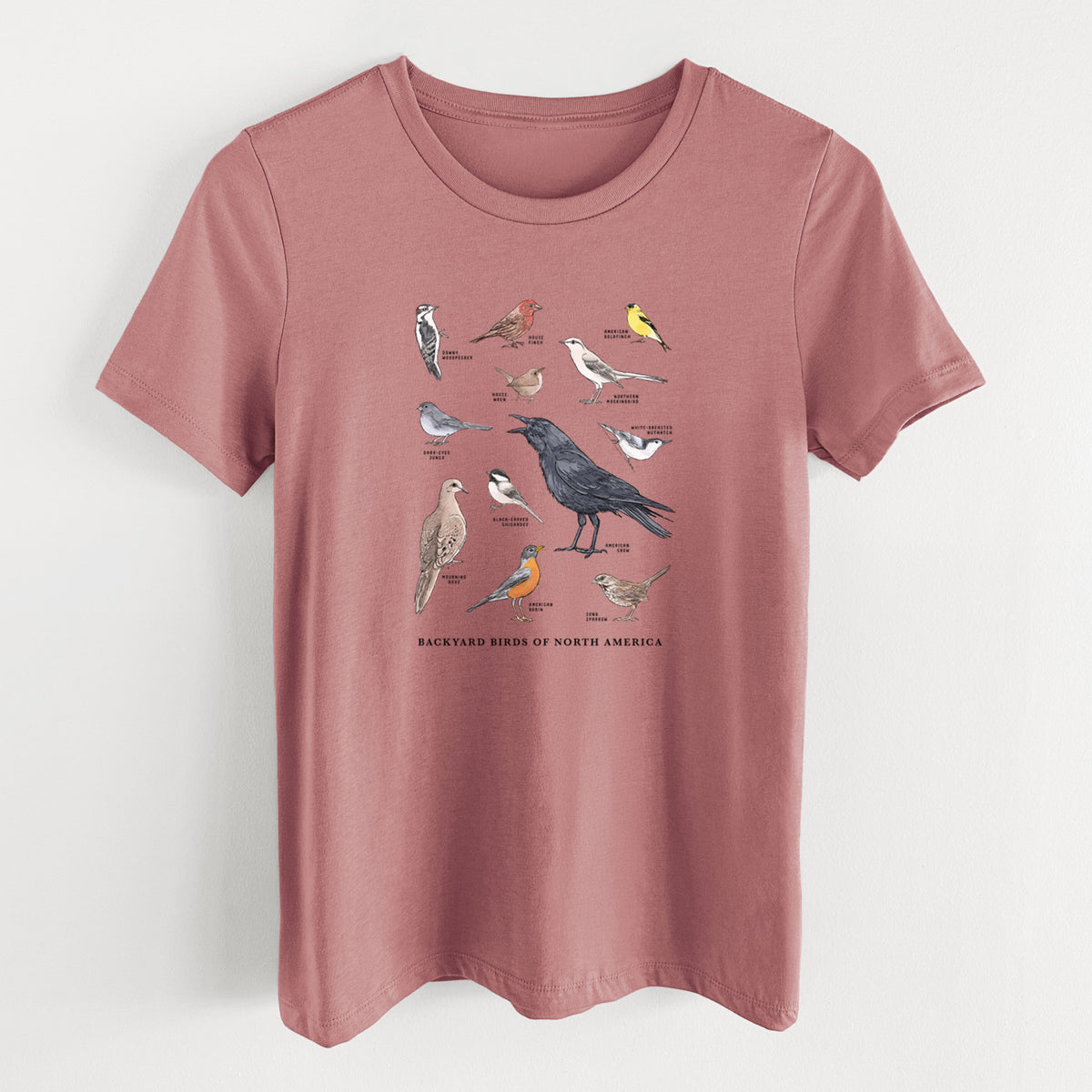 Mauve pink women's relaxed fit cotton t-shirt laid flat, printed with a full-color chart of North American backyard birds, each labeled with its species.