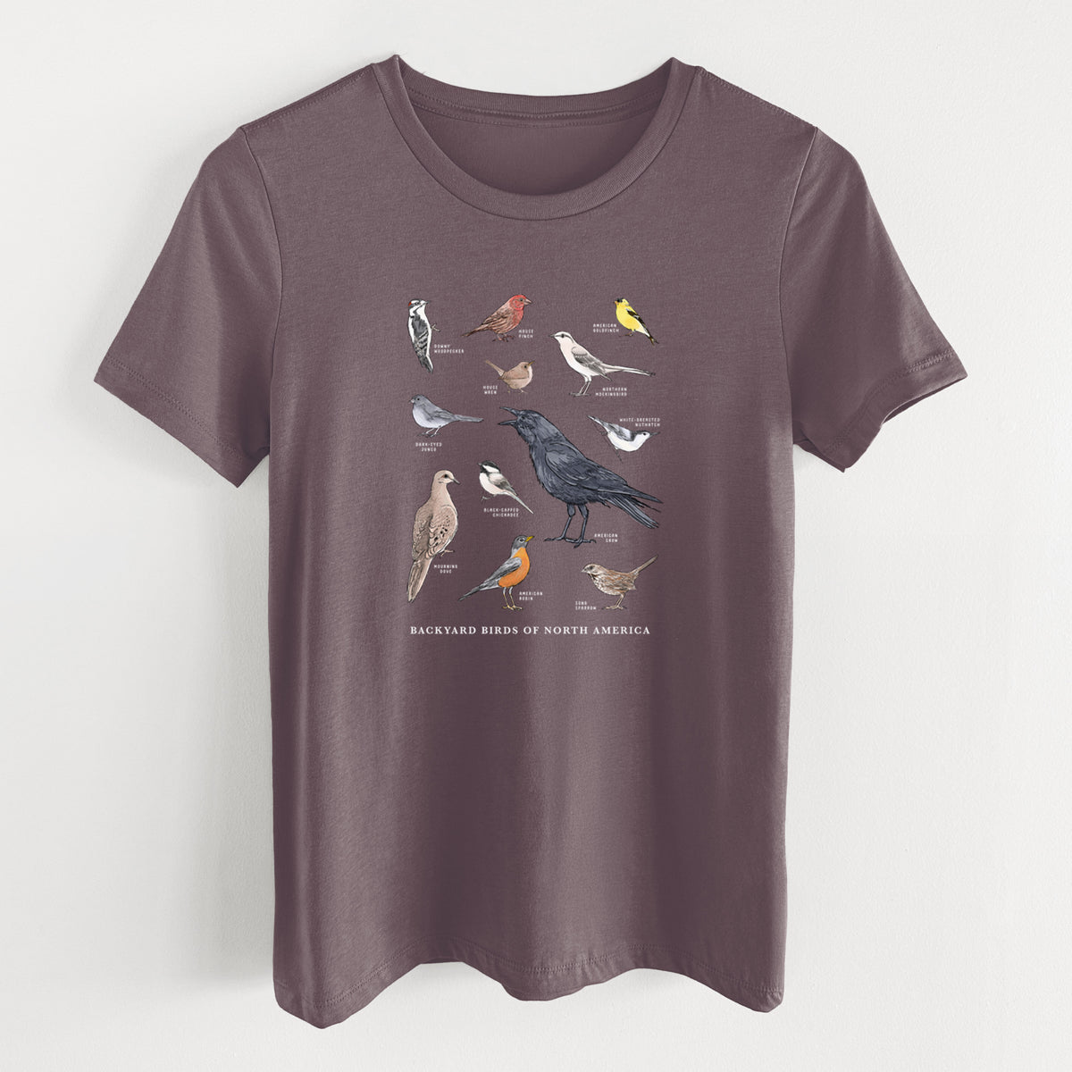 Purple storm women's relaxed fit cotton t-shirt laid flat, printed with a full-color chart of North American backyard birds, each labeled with its species.