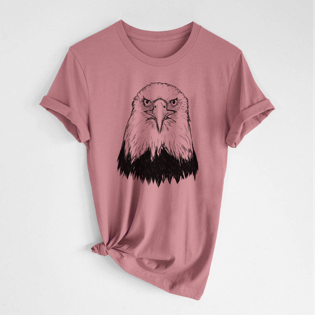 Mauve pink lightweight cotton t-shirt laid flat with the sleeves rolled, printed with a detailed black ink portrait of a bald eagle facing forward.