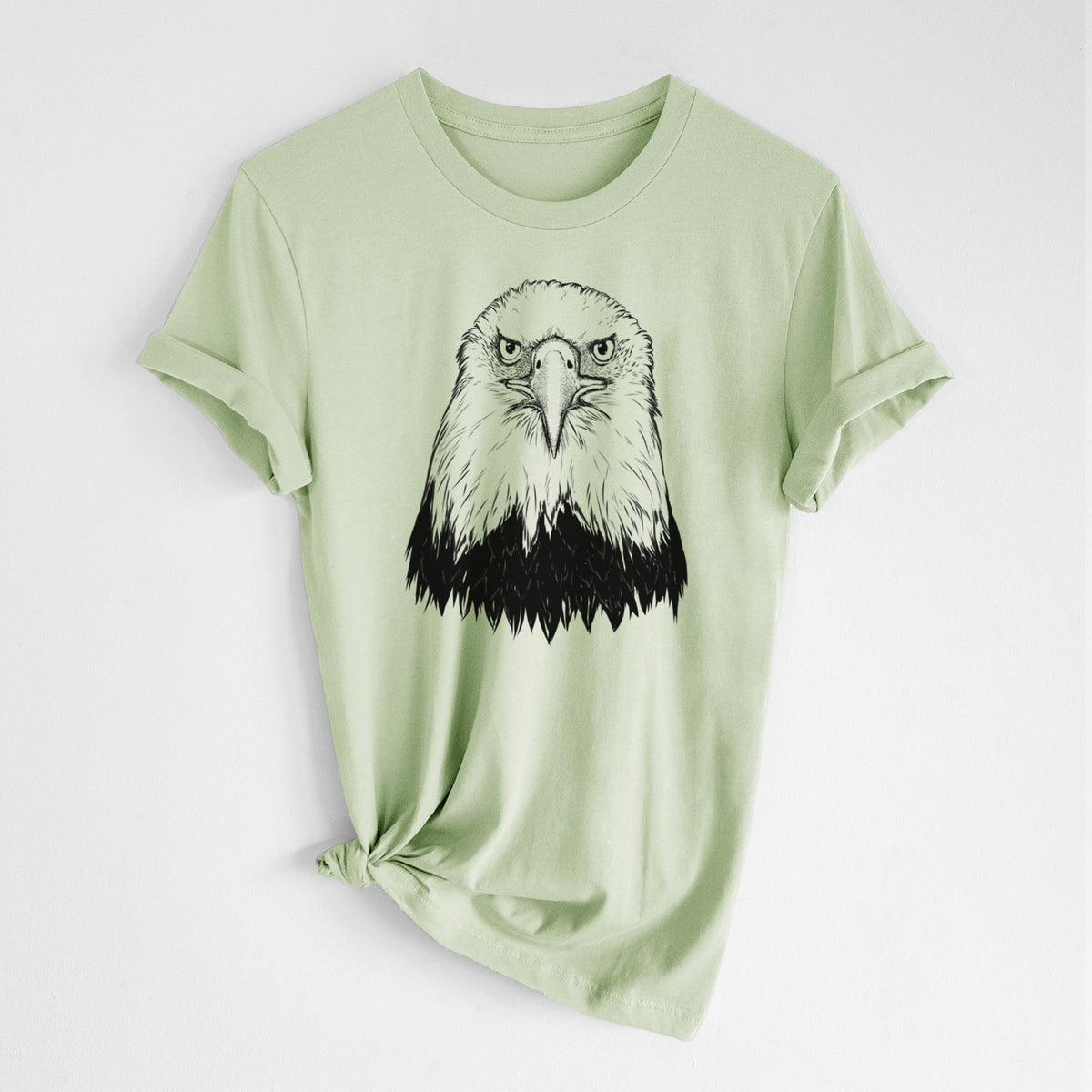 Spring green lightweight cotton t-shirt laid flat with the sleeves rolled, printed with a detailed black ink portrait of a bald eagle facing forward.