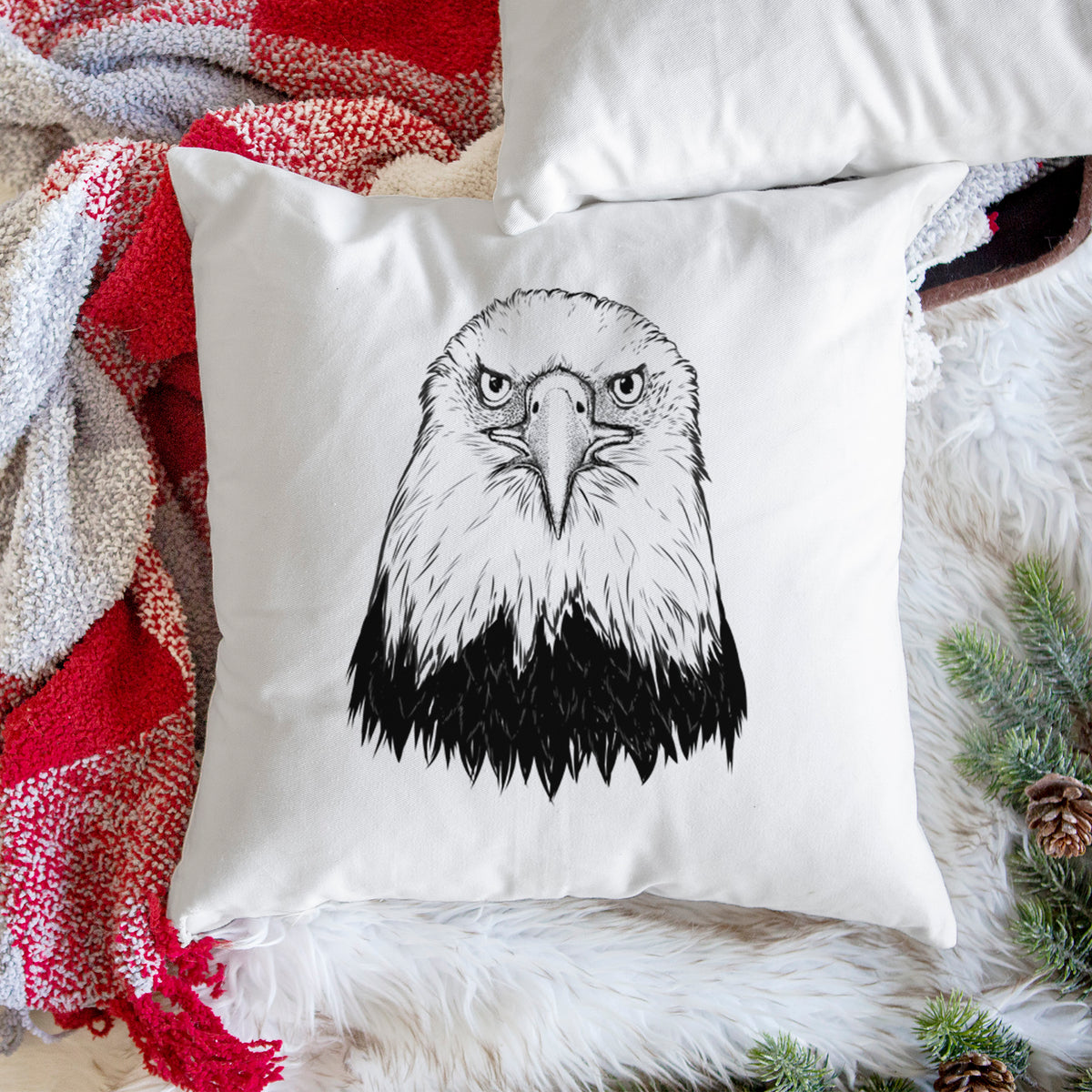 White pillow cover printed with a detailed black ink portrait of a bald eagle facing forward, on a woven chair.