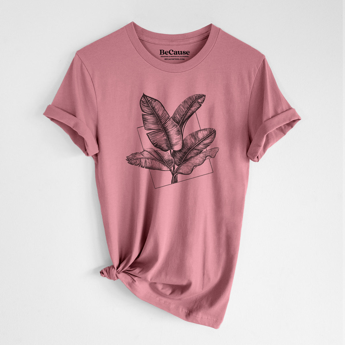 Mauve pink lightweight cotton t-shirt laid flat with the sleeves rolled, printed with a black ink illustration of banana leaves in front of a square outline.