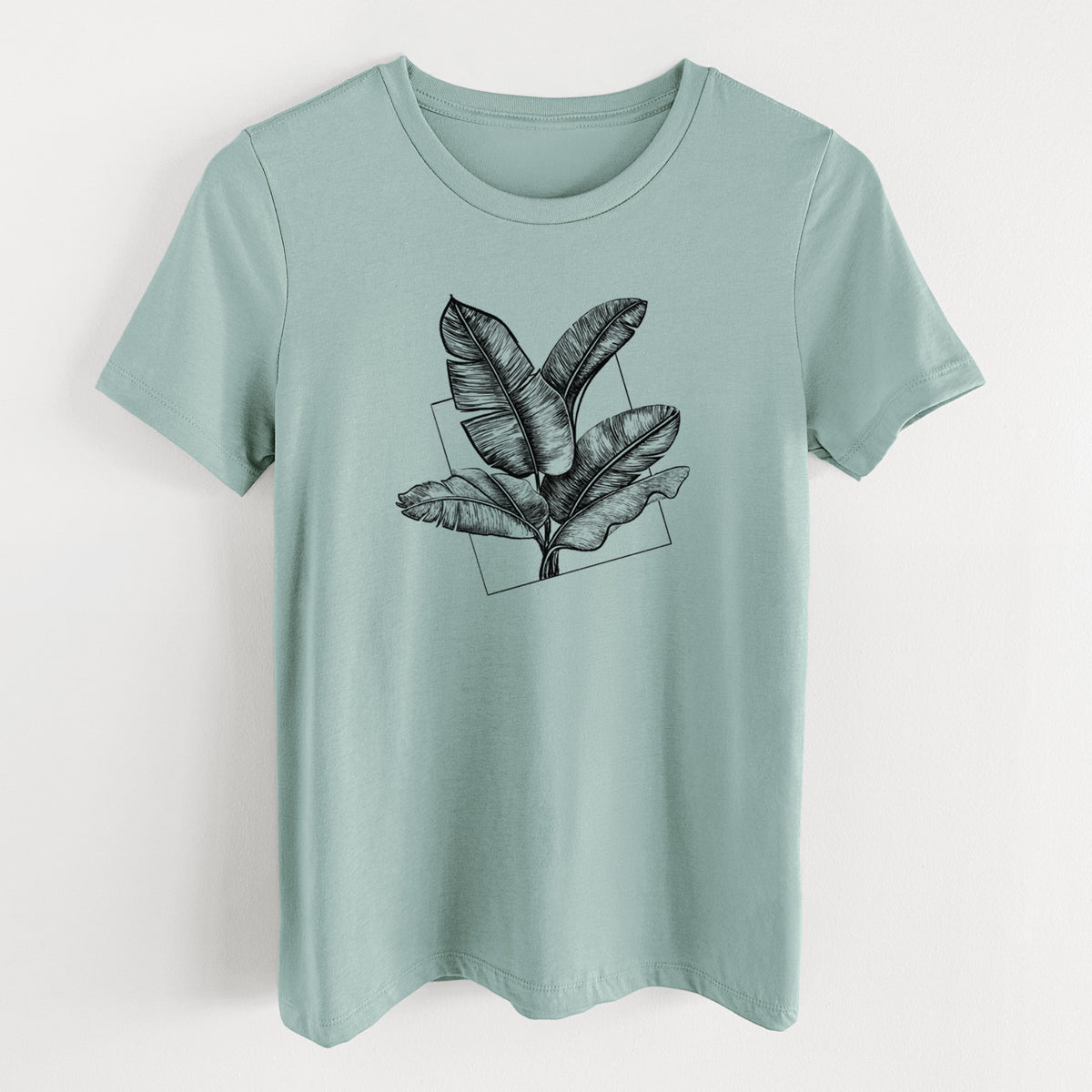 Dusty blue women's relaxed fit cotton t-shirt laid flat, printed with a black ink illustration of banana leaves in front of a square outline.