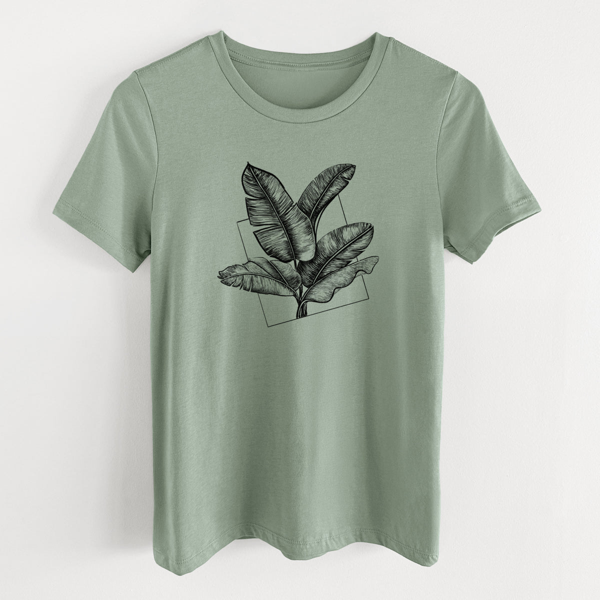 Sage green women's relaxed fit cotton t-shirt laid flat, printed with a black ink illustration of banana leaves in front of a square outline.