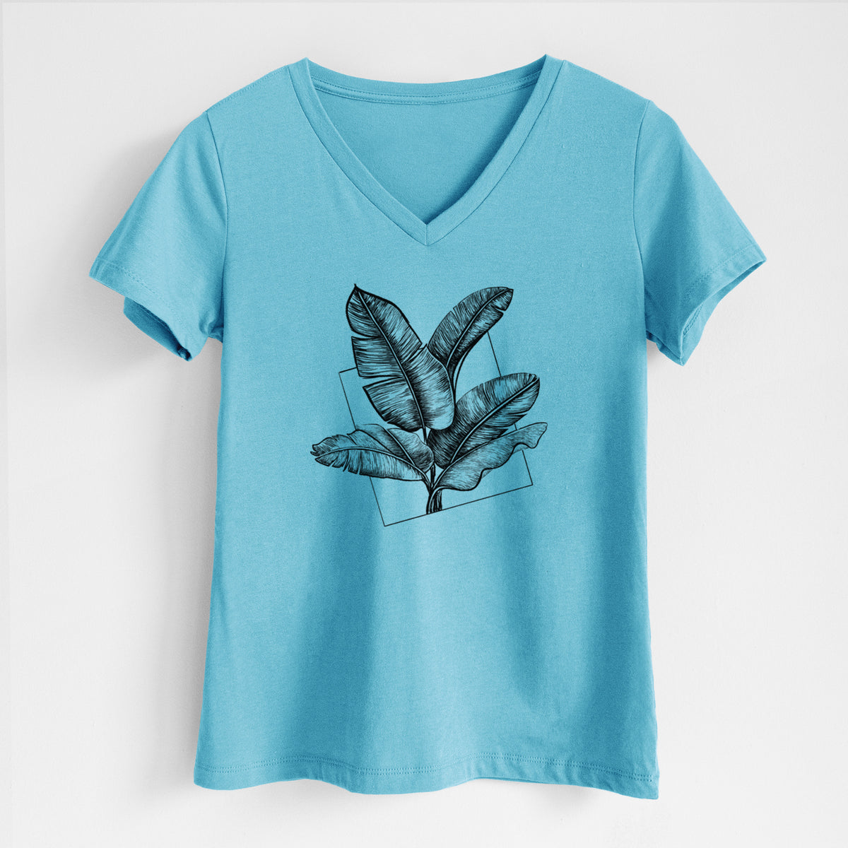 Turquoise women's relaxed fit cotton V-neck t-shirt laid flat, printed with a black ink illustration of banana leaves in front of a square outline.
