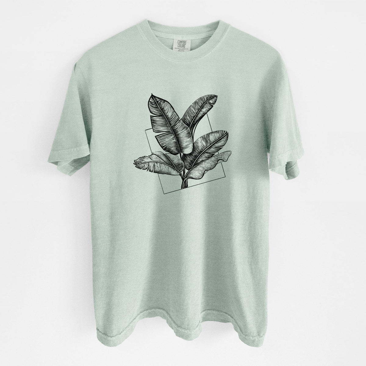 Bay green Comfort Colors t-shirt laid flat, printed with a black ink illustration of banana leaves in front of a square outline.