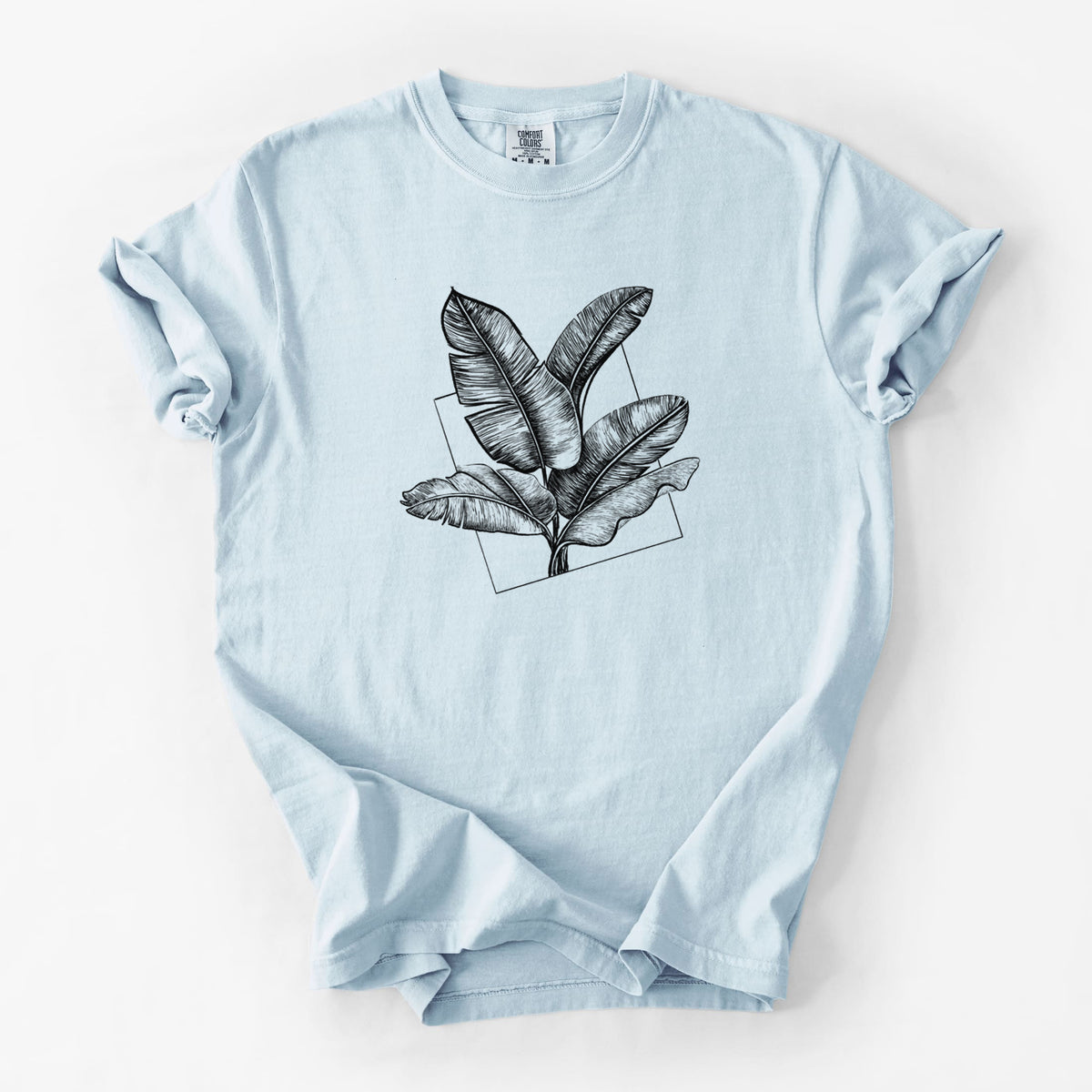 Chambray blue Comfort Colors t-shirt laid flat, printed with a black ink illustration of banana leaves in front of a square outline.