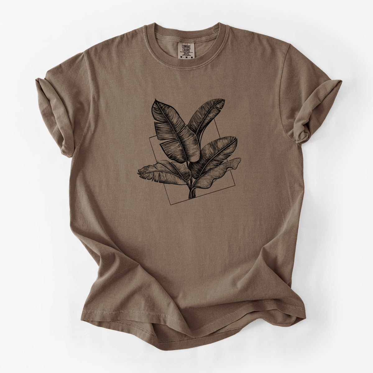 Espresso brown Comfort Colors t-shirt laid flat, printed with a black ink illustration of banana leaves in front of a square outline.