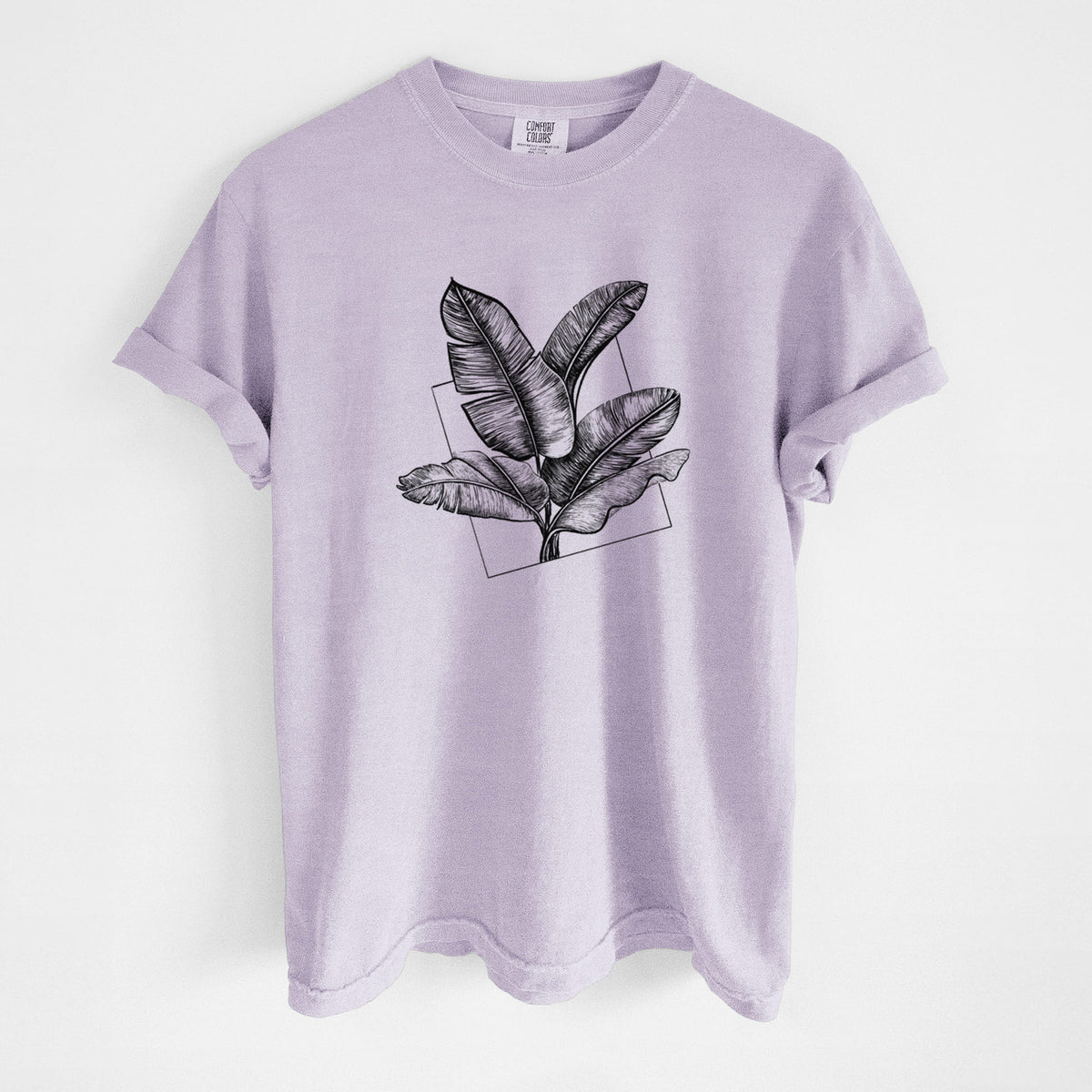 Orchid purple Comfort Colors t-shirt laid flat, printed with a black ink illustration of banana leaves in front of a square outline.