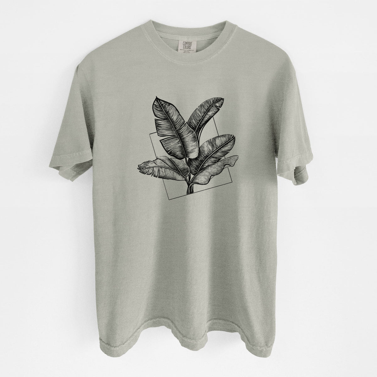 Sandstone beige Comfort Colors t-shirt laid flat, printed with a black ink illustration of banana leaves in front of a square outline.