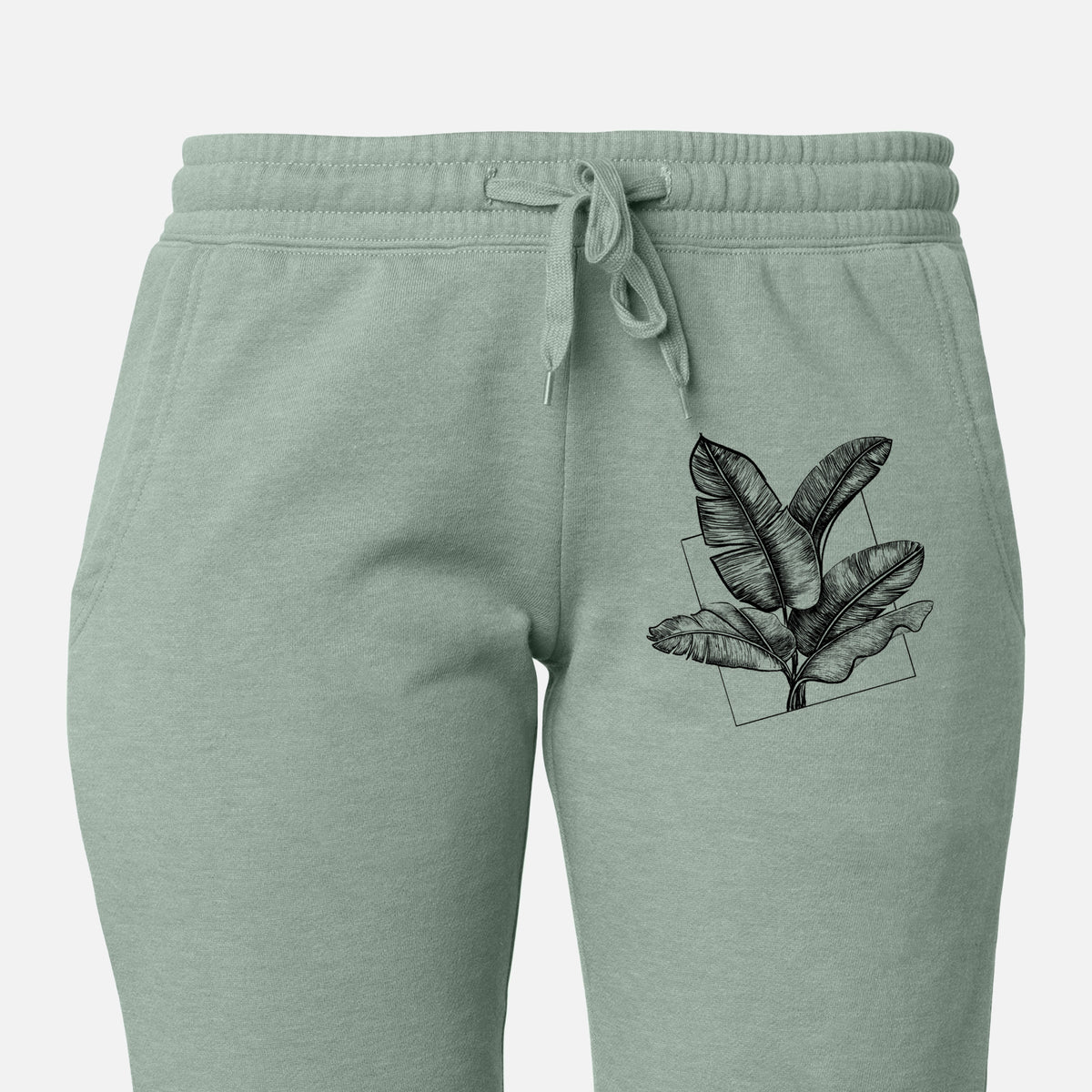 Front of sage green Cali Wave sweatpants, printed with a black ink illustration of banana leaves in front of a square outline on the leg.