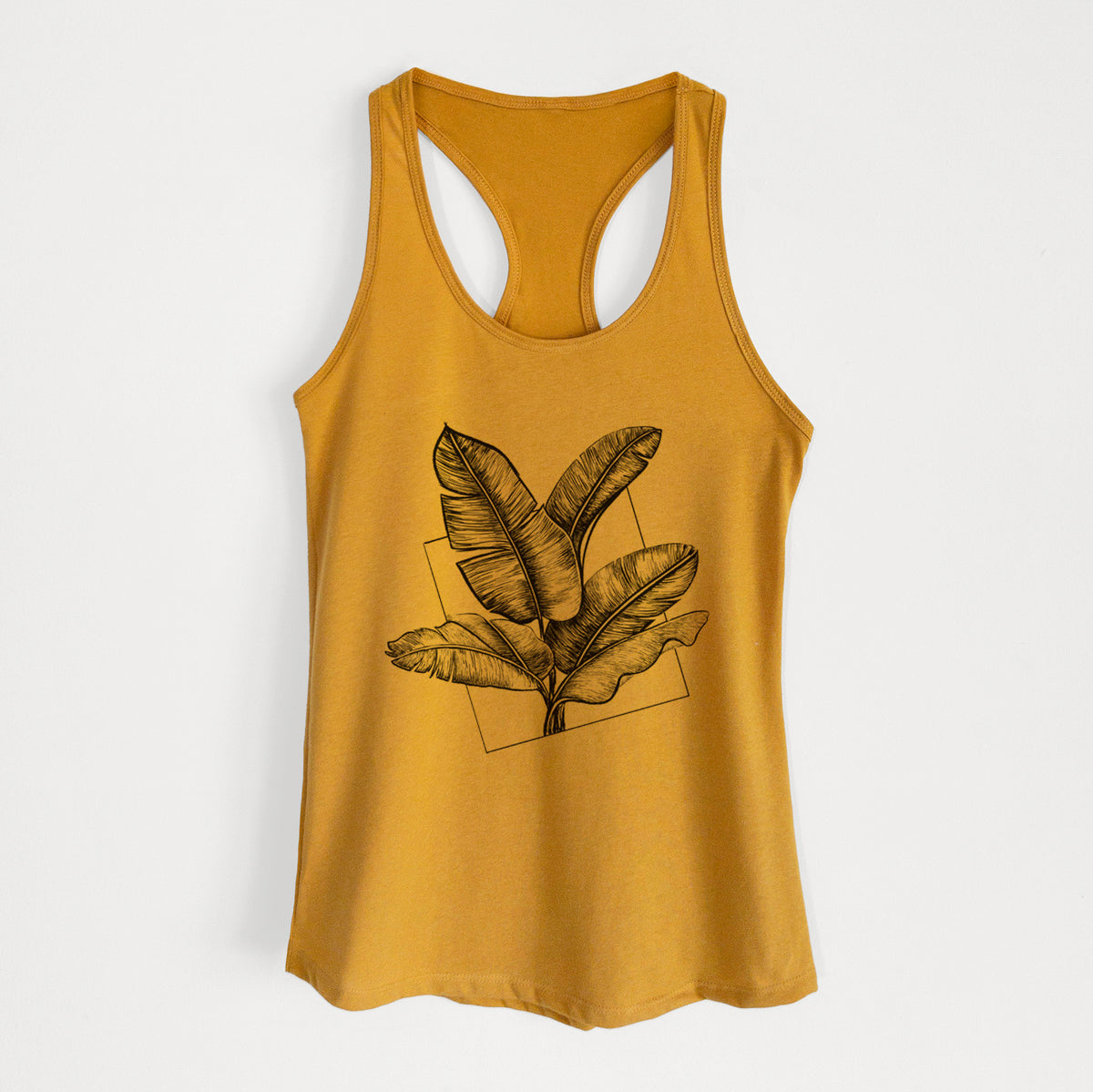 Gold women's racerback tank top laid flat, printed with a black ink illustration of banana leaves in front of a square outline.