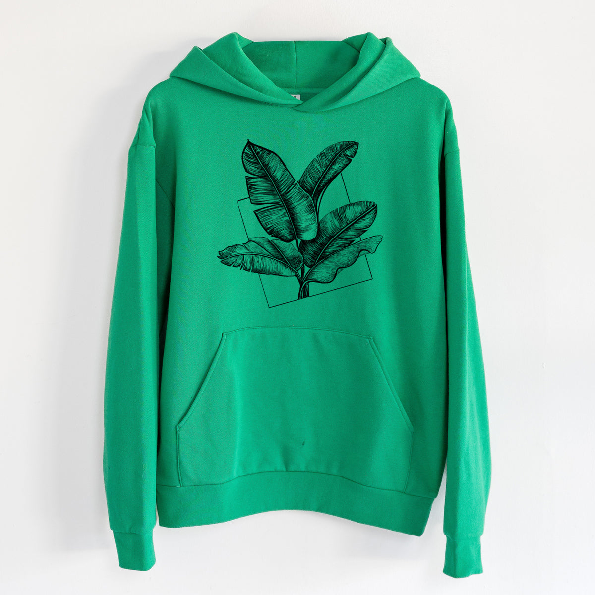 Banana Plant Leaves - Statement Midweight Hoodie in Kelly Green, hanging on a white wall, with a front kangaroo pocket and no drawcords.