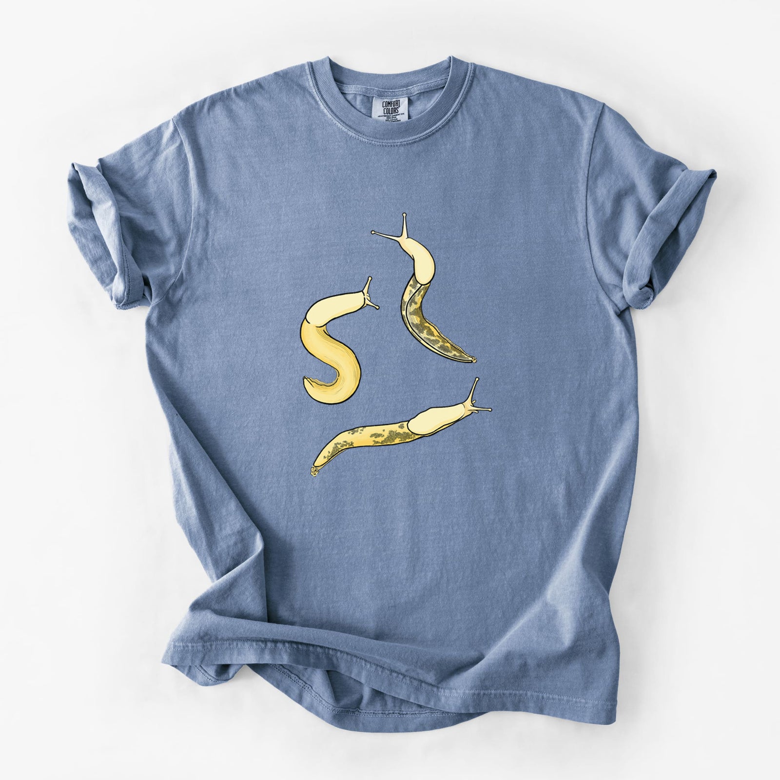 Blue jean Comfort Colors t-shirt laid flat, printed with a full-color illustration of three yellow banana slugs.