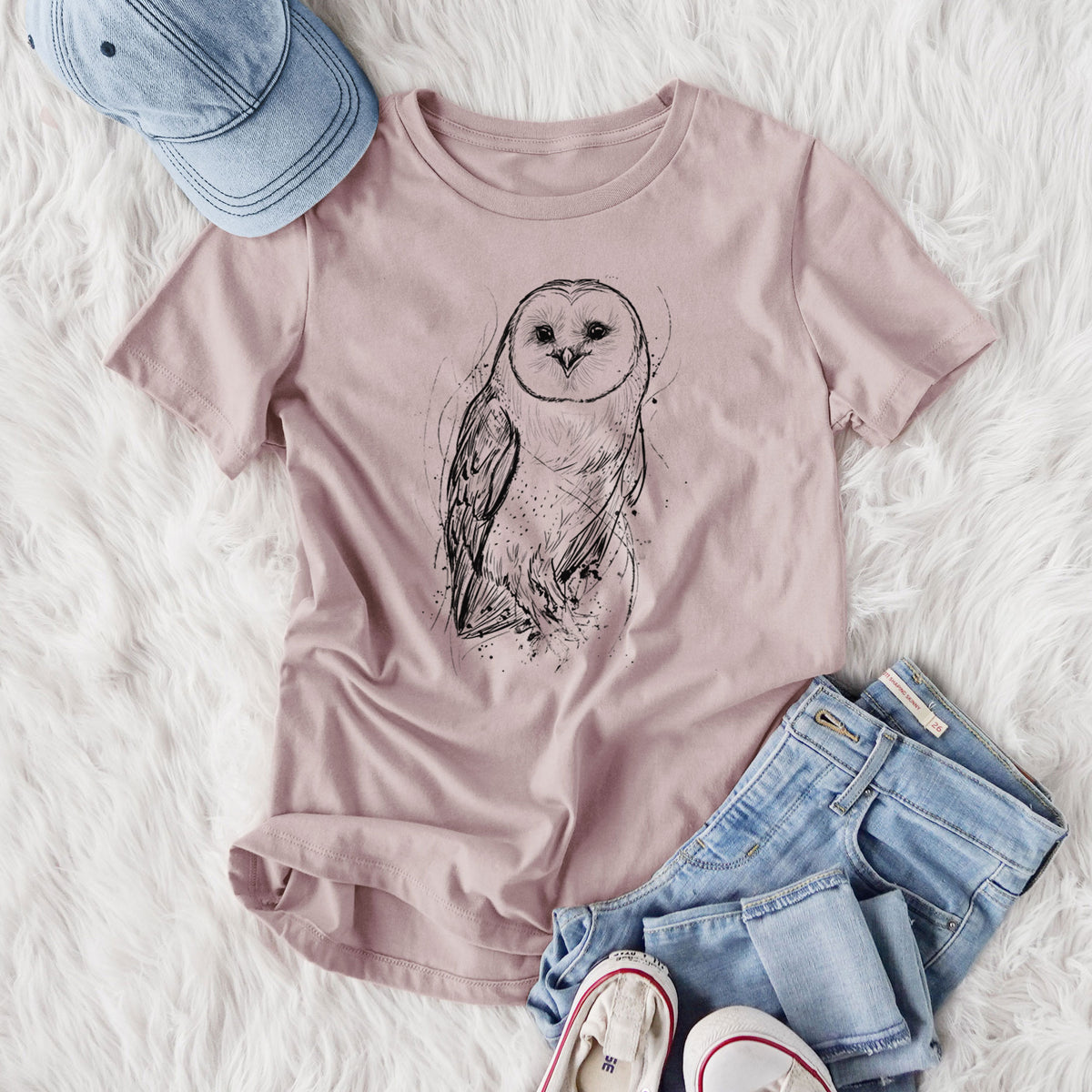 Women's relaxed fit cotton t-shirt printed with a detailed black ink illustration of a barn owl standing and facing forward, styled flat on a white faux fur rug with jeans.