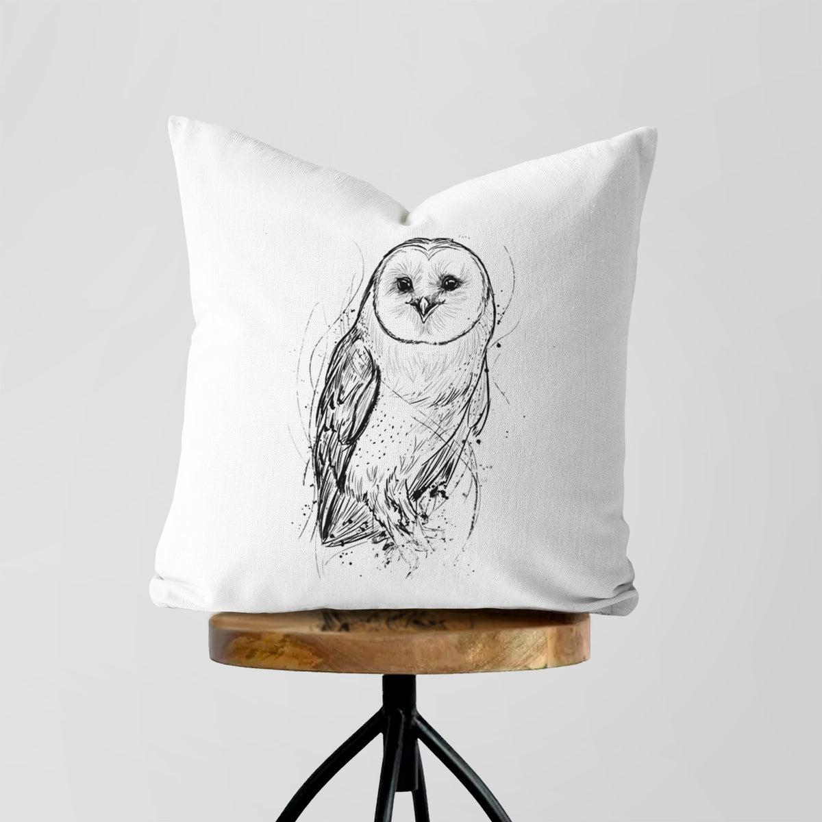 White pillow cover printed with a detailed black ink illustration of a barn owl standing and facing forward, on a wooden stool.