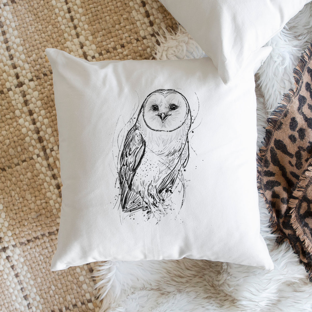 White pillow cover printed with a detailed black ink illustration of a barn owl standing and facing forward, on a woven chair.