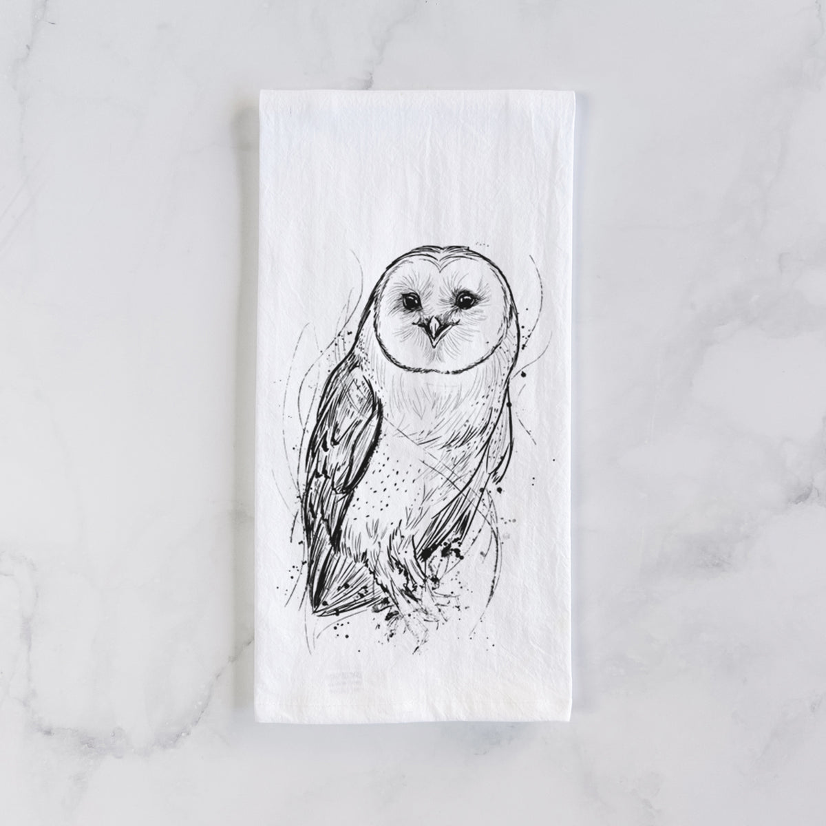 White cotton tea towel laid flat on marble, printed with a detailed black ink illustration of a barn owl standing and facing forward.