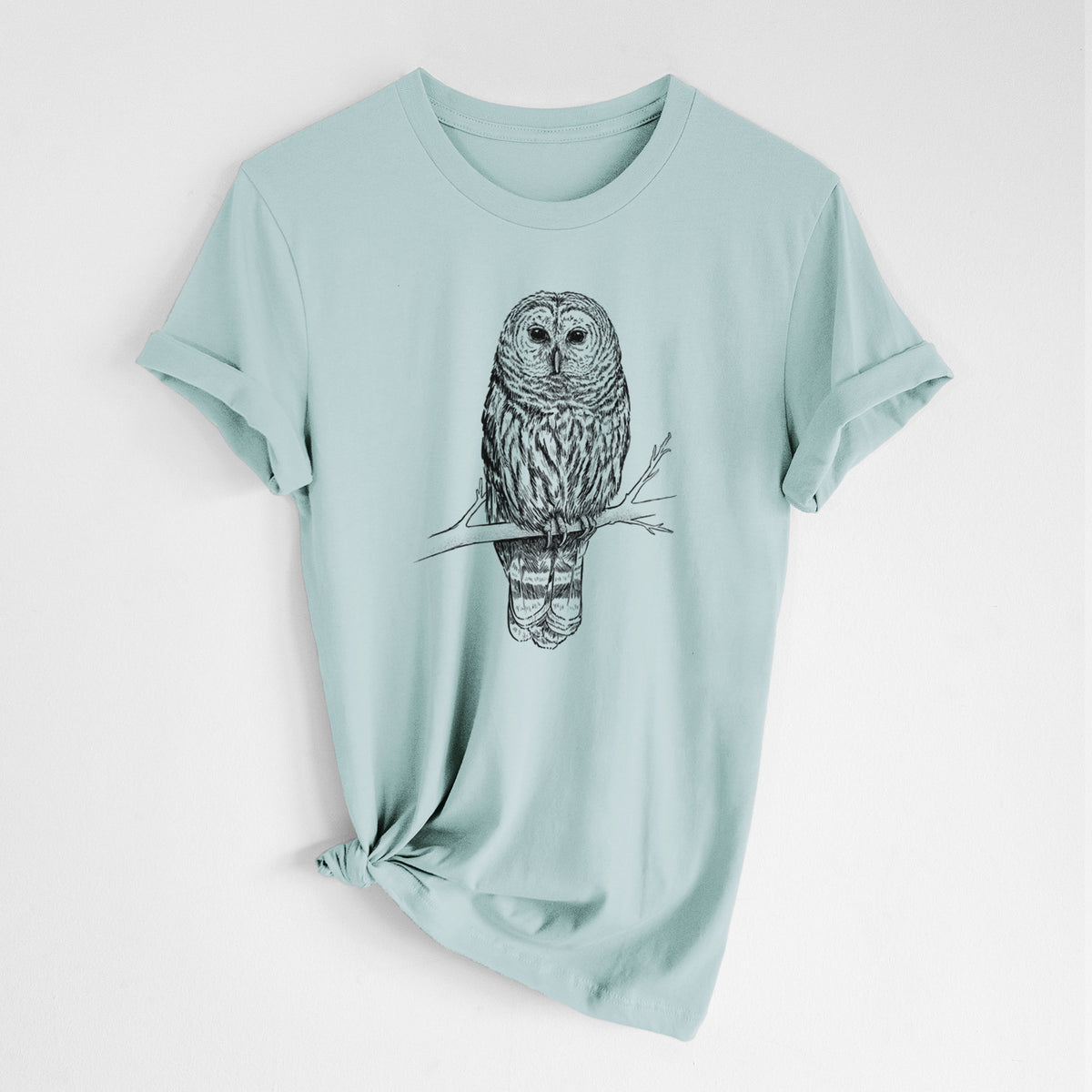 Dusty blue lightweight cotton t-shirt laid flat with the sleeves rolled, printed with a detailed black ink illustration of a barred owl perched on a branch.