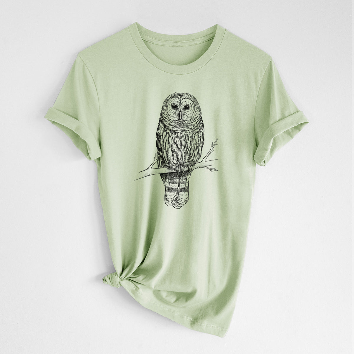 Spring green lightweight cotton t-shirt laid flat with the sleeves rolled, printed with a detailed black ink illustration of a barred owl perched on a branch.