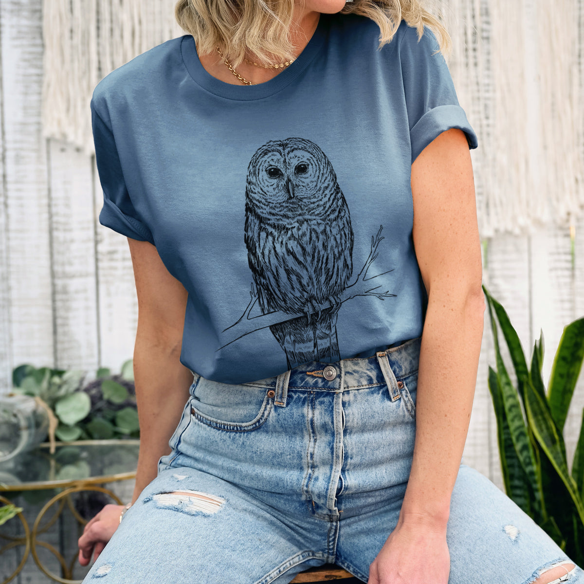 Woman wearing a steel blue lightweight cotton t-shirt printed with a detailed black ink illustration of a barred owl perched on a branch.