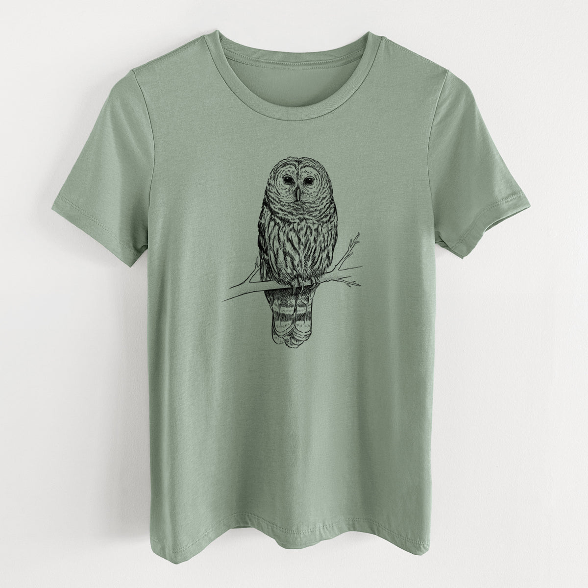 Sage green women's relaxed fit cotton t-shirt laid flat, printed with a detailed black ink illustration of a barred owl perched on a branch.
